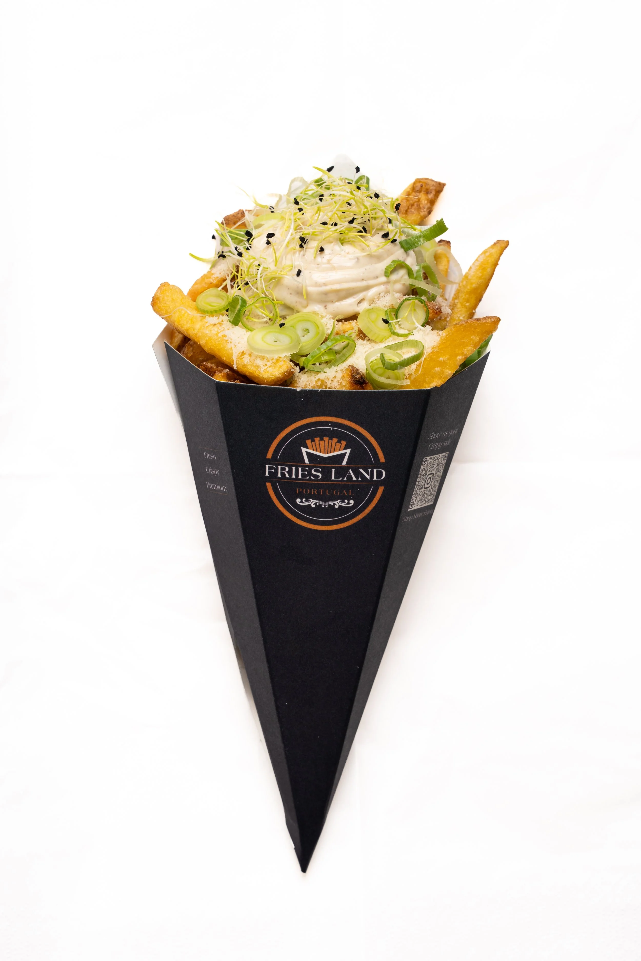 A serving of French fries with toppings including diced green onions, microgreens, and a creamy sauce, in a black paper holder labeled 'Fries Land Portugal'.