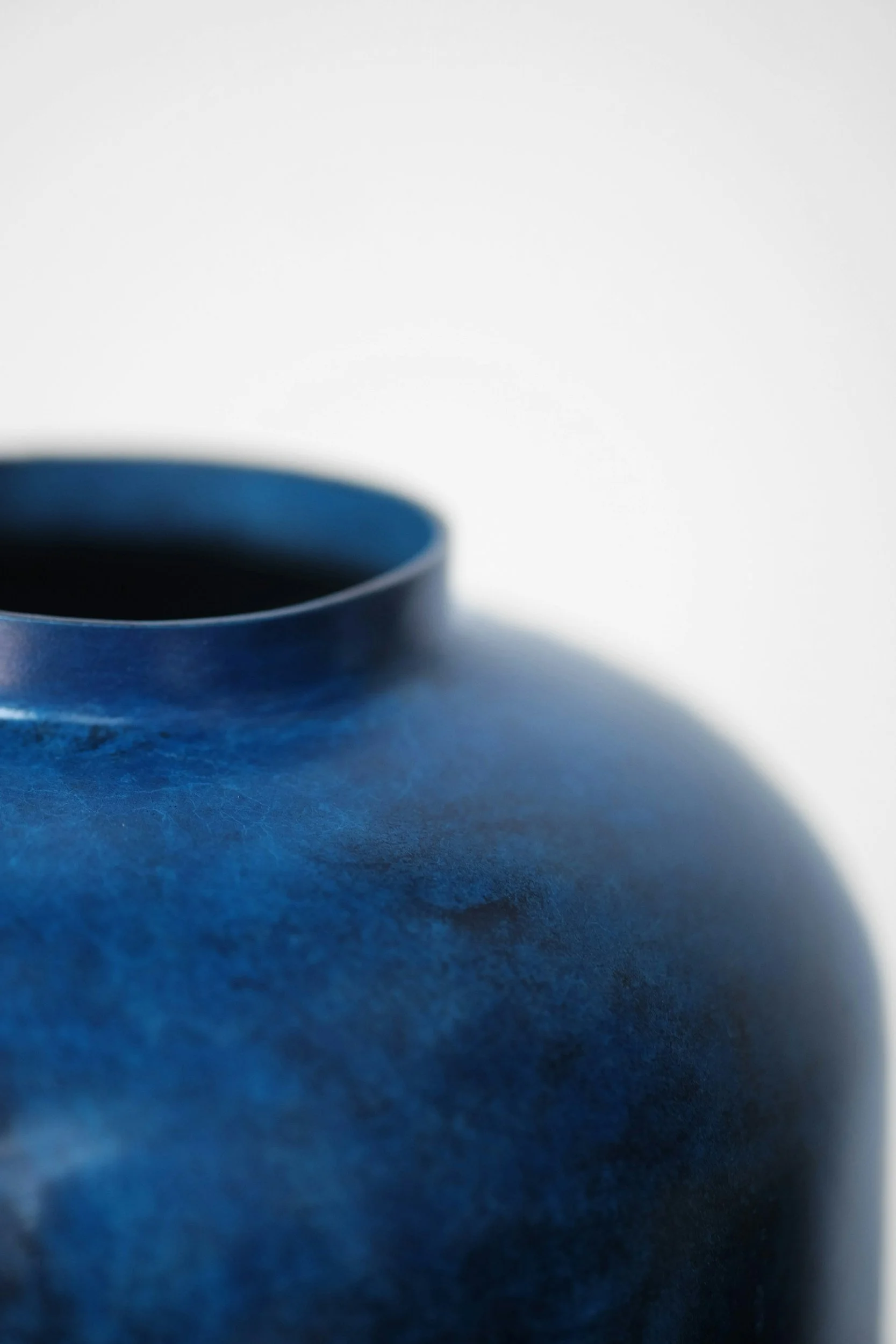 Close-up of a blue mug on a textured blue surface with a white background.