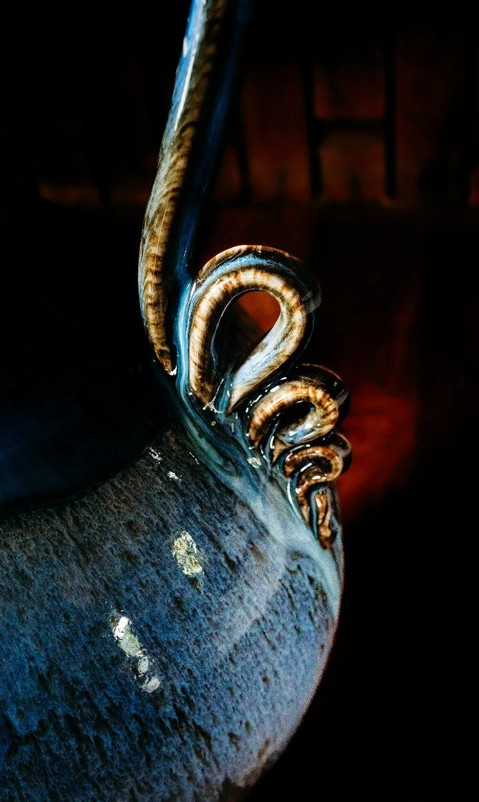 Close-up of a decorative, metallic object with intricate swirl details, dark background.