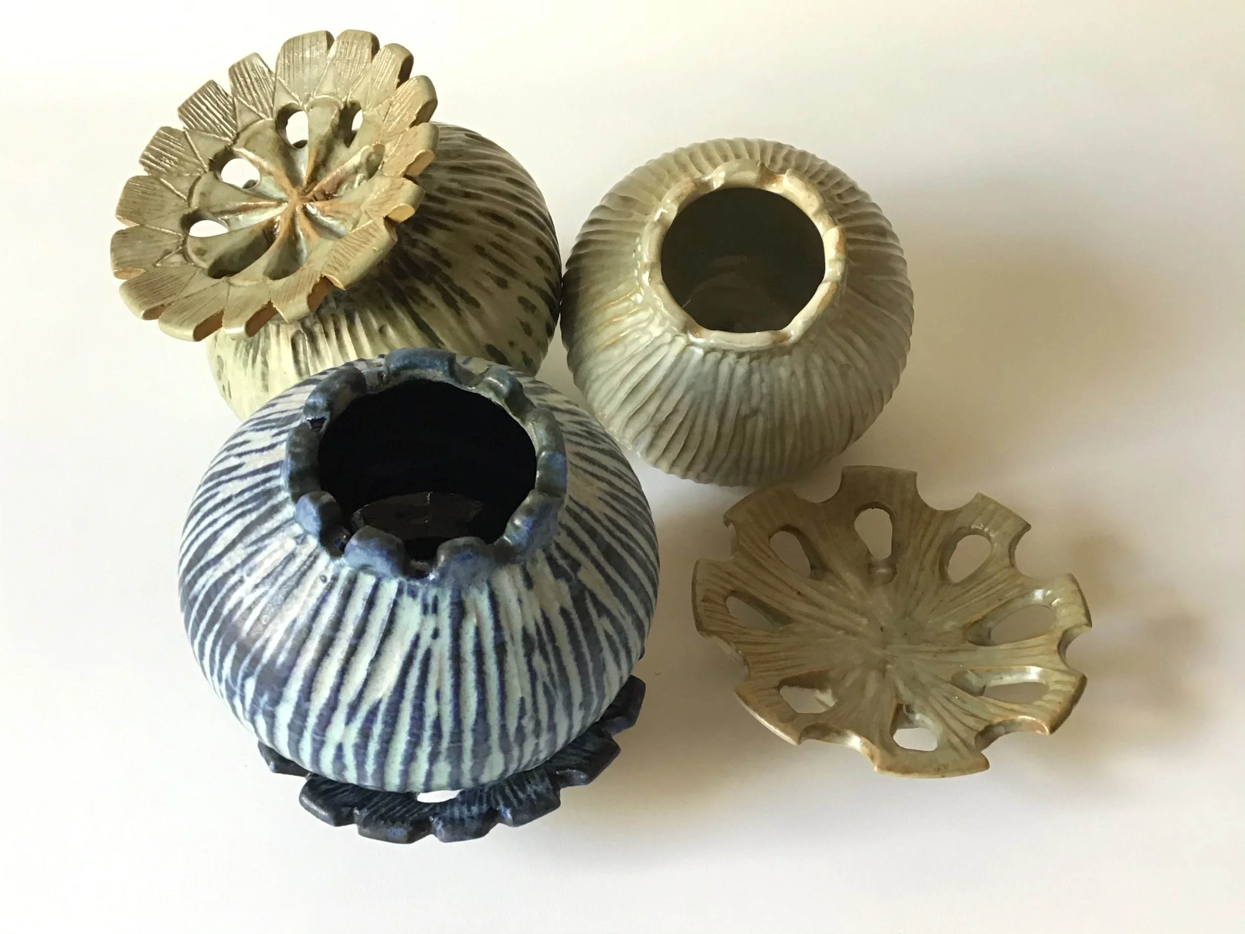 A collection of decorative ceramic vases with various textures and colors, arranged against a plain background.