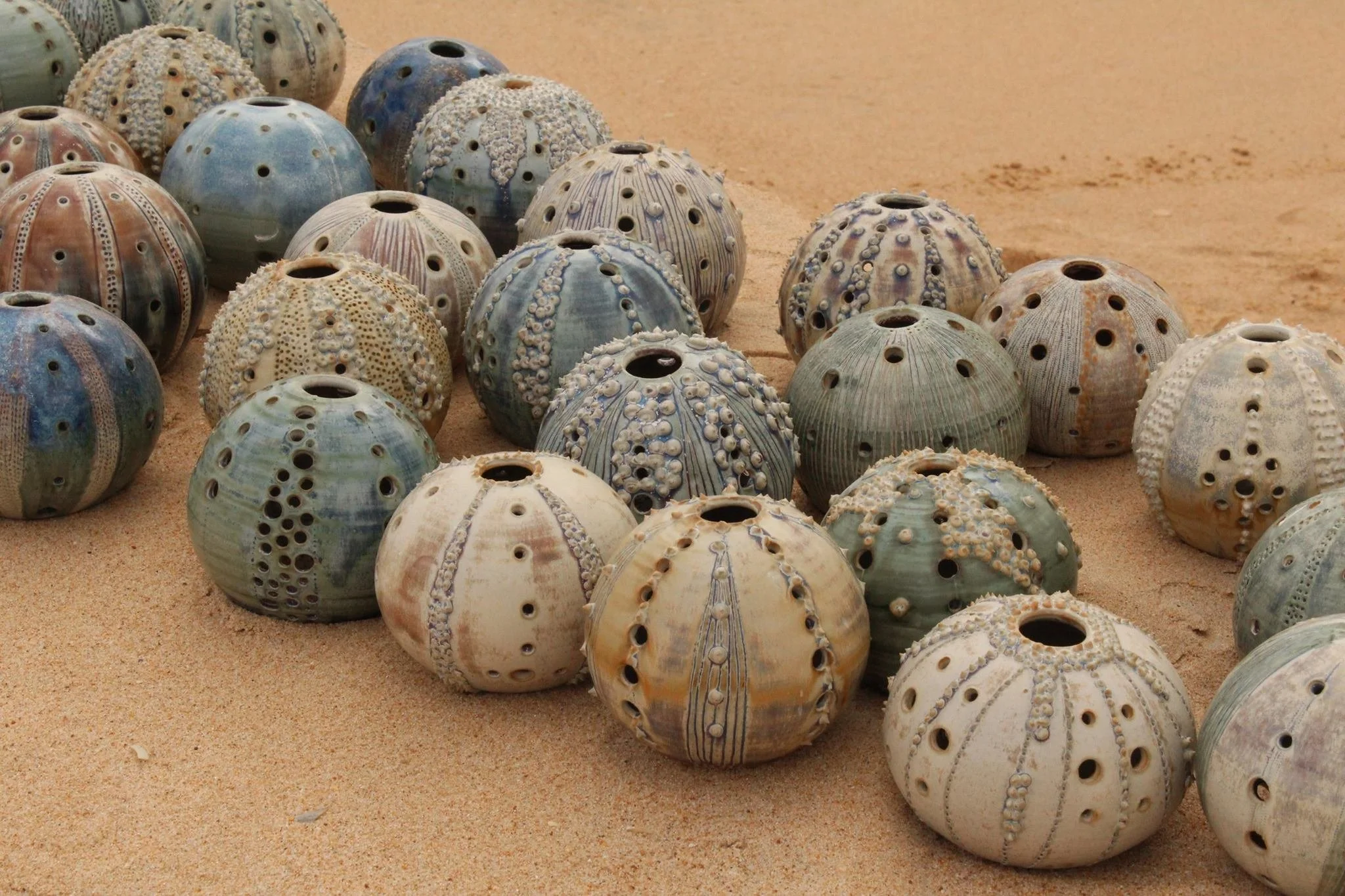 A collection of various sea urchin shells scattered on a sandy surface.