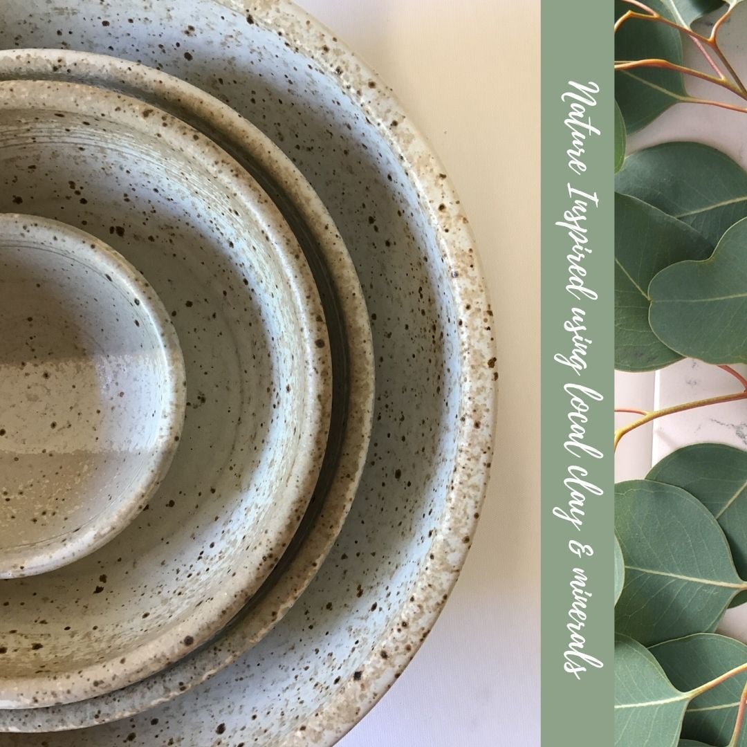 Set of three speckled ceramic bowls in graduated sizes with a leafy plant on the side, and text overlay saying "Natural Textured Wall & Ovenware" in white.