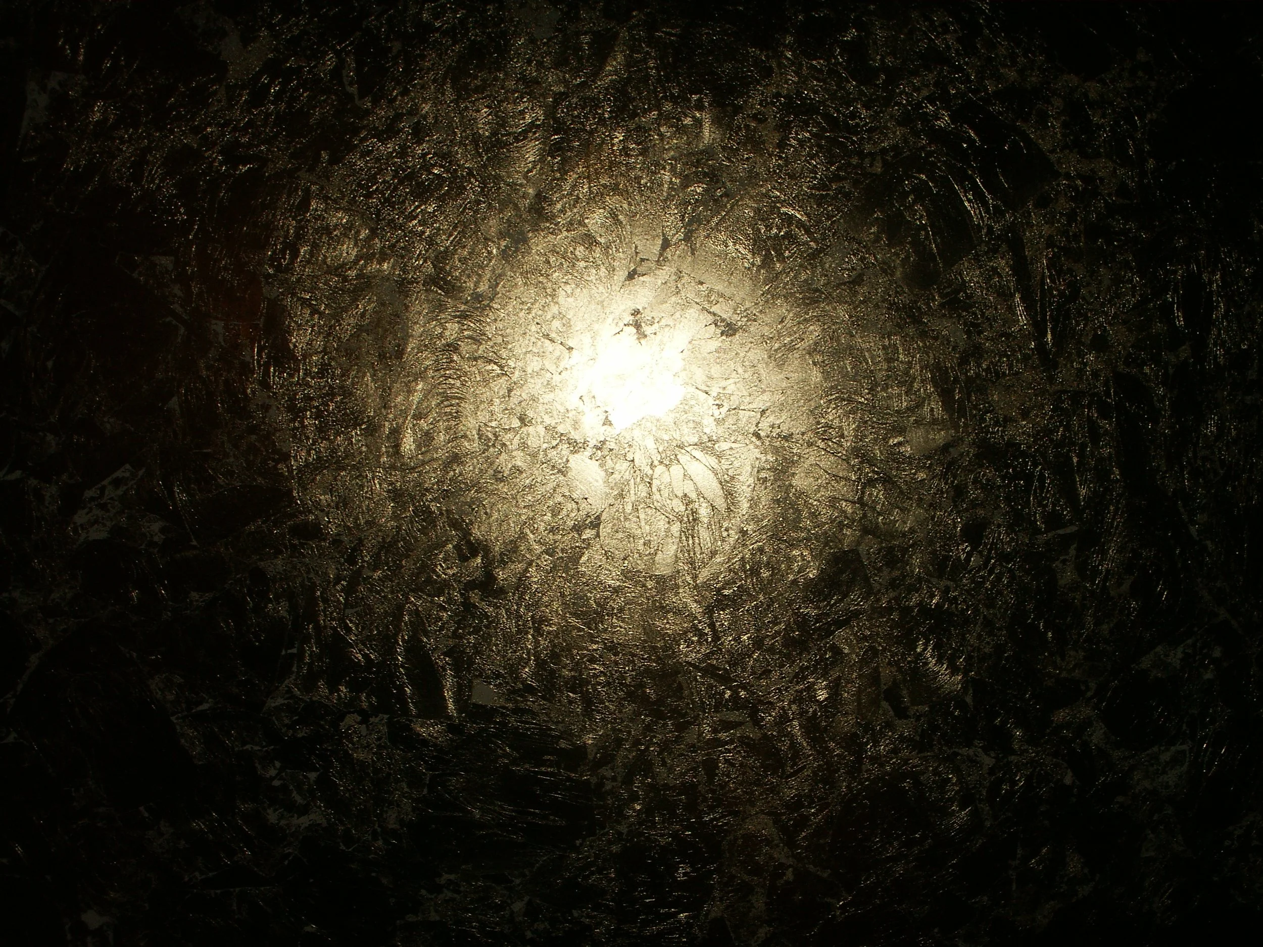 A dark surface with a textured, metallic appearance illuminated from below, creating a shiny and reflective effect.