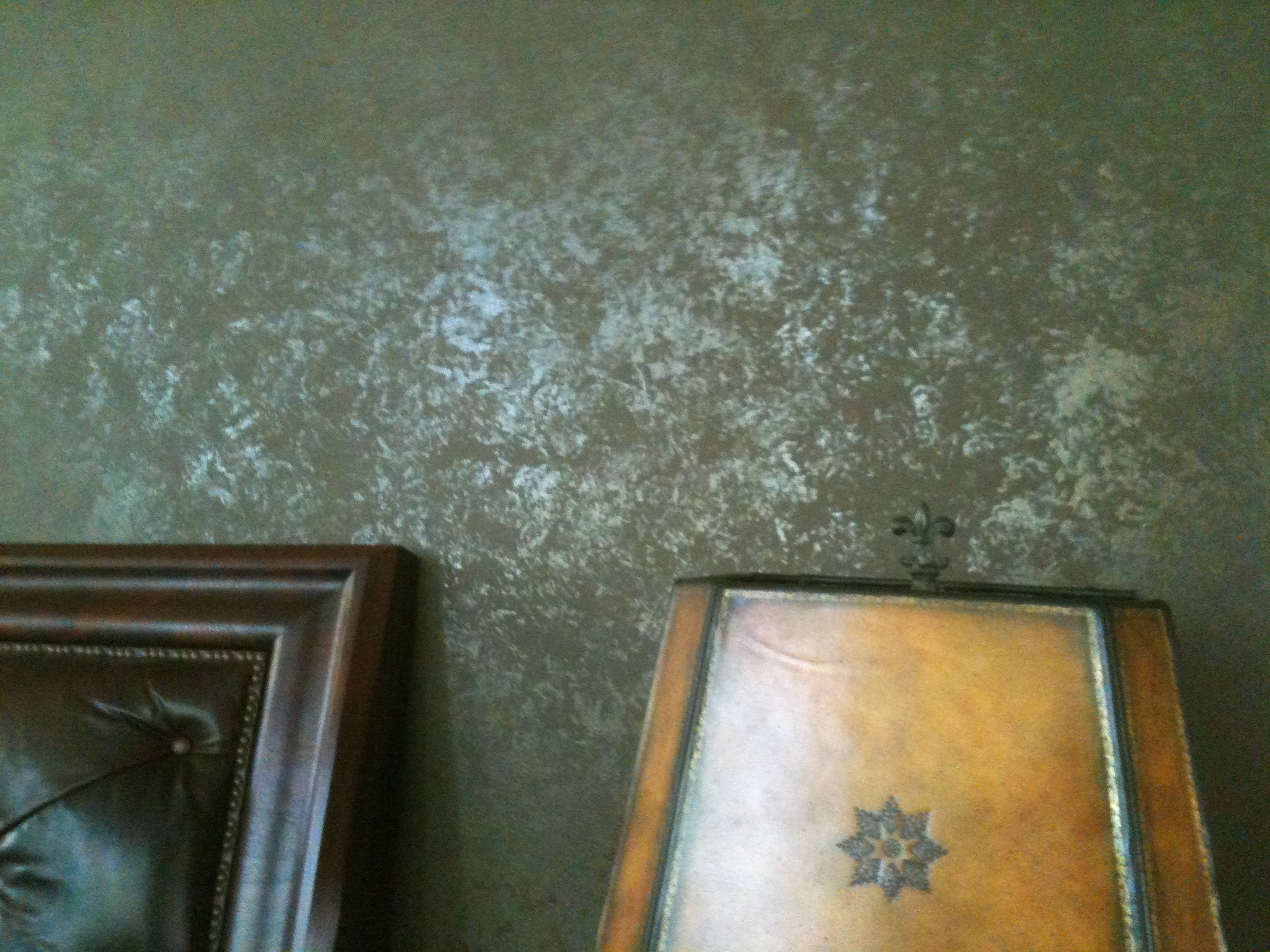 A dark, textured floor with patterns, along with furniture including the bottom part of a dark upholstered armchair or sofa with decorative nailhead trim on the left side, and a wooden table or cabinet at the bottom right corner.