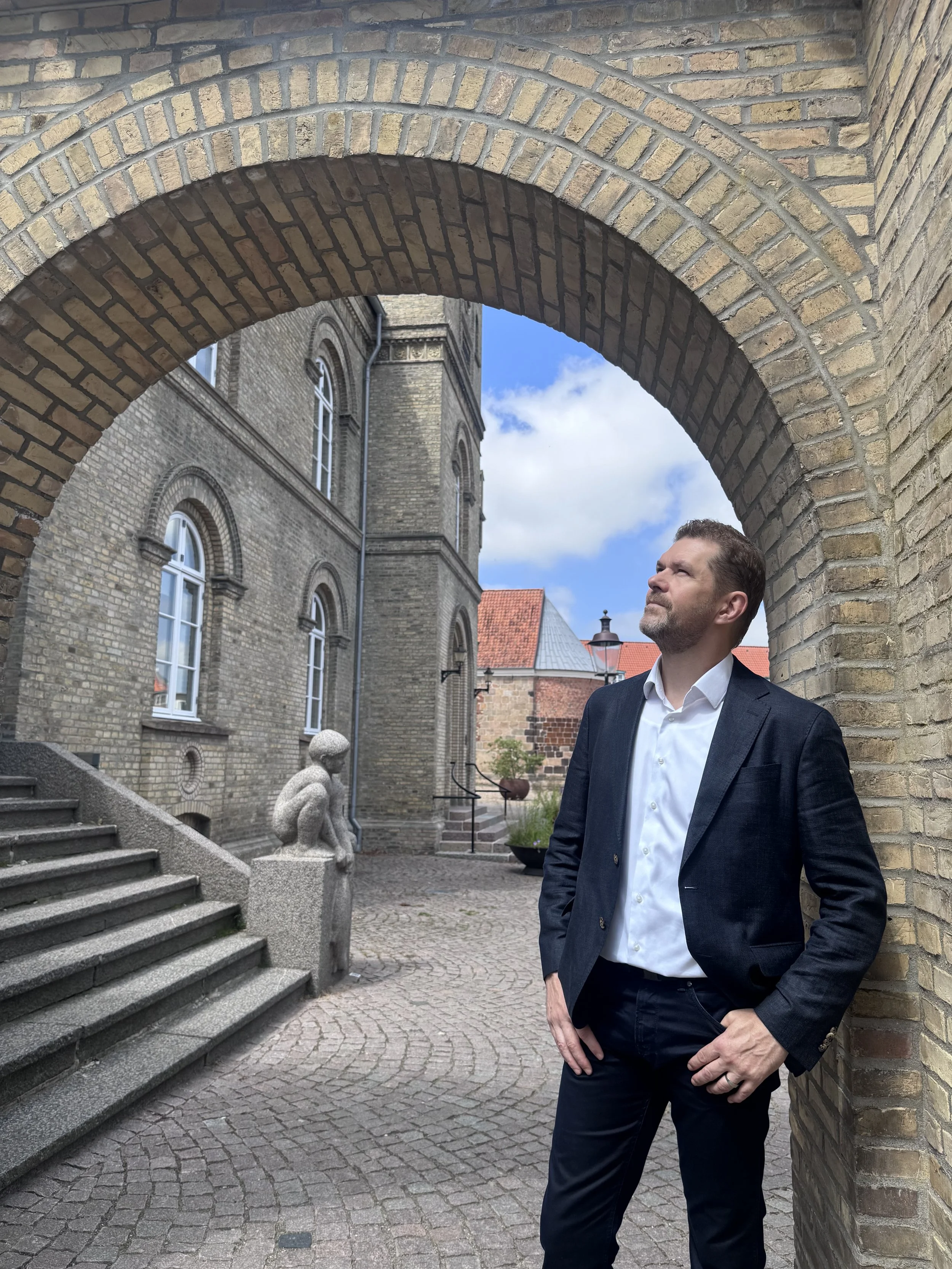 Bjarki Ágústsson standing beneath a brick archway in Denmark.
