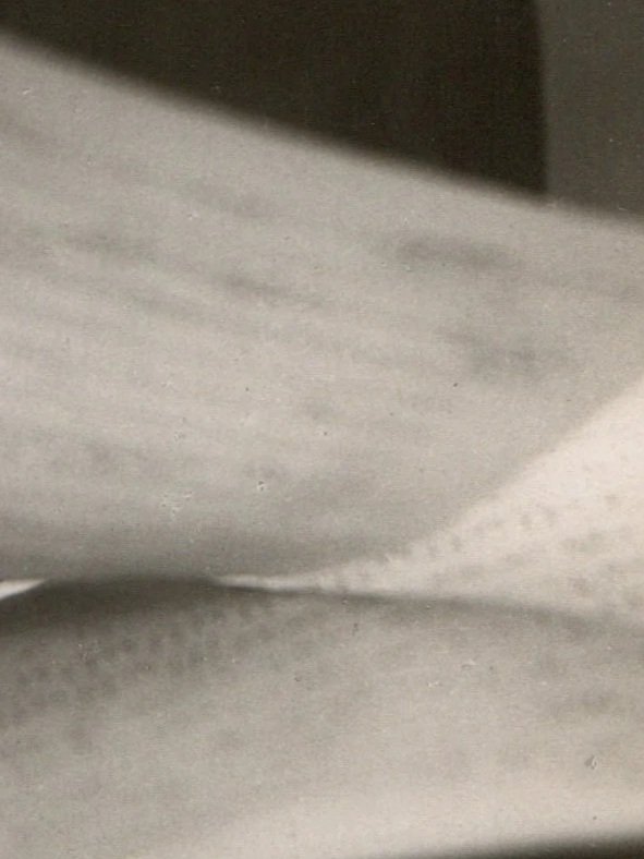 Close-up of a textured, light gray surface with some shadows and shadows forming an abstract pattern.