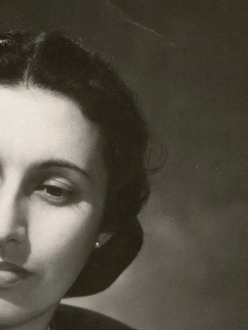 Close-up black and white photo of a woman's face partially visible, with dark hair and makeup.