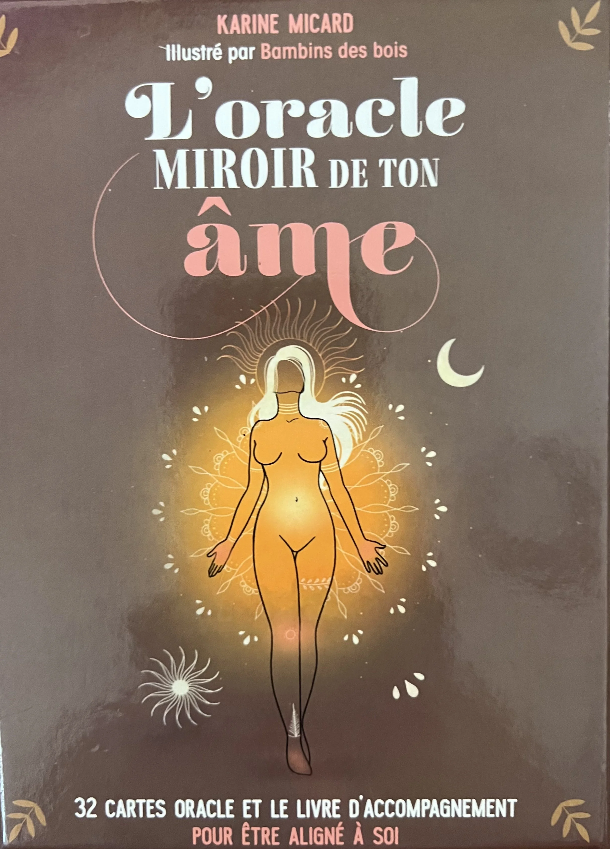 Couverture d'un livre intitulé "L'oracle miroir de ton âme" illustré par Bambins des bois, avec une illustration d'une femme nue assise en méditation, entourée de motifs floraux, de la lune et du soleil, avec le texte mentionnant 32 cartes oracle et un guide d'accompagnement.