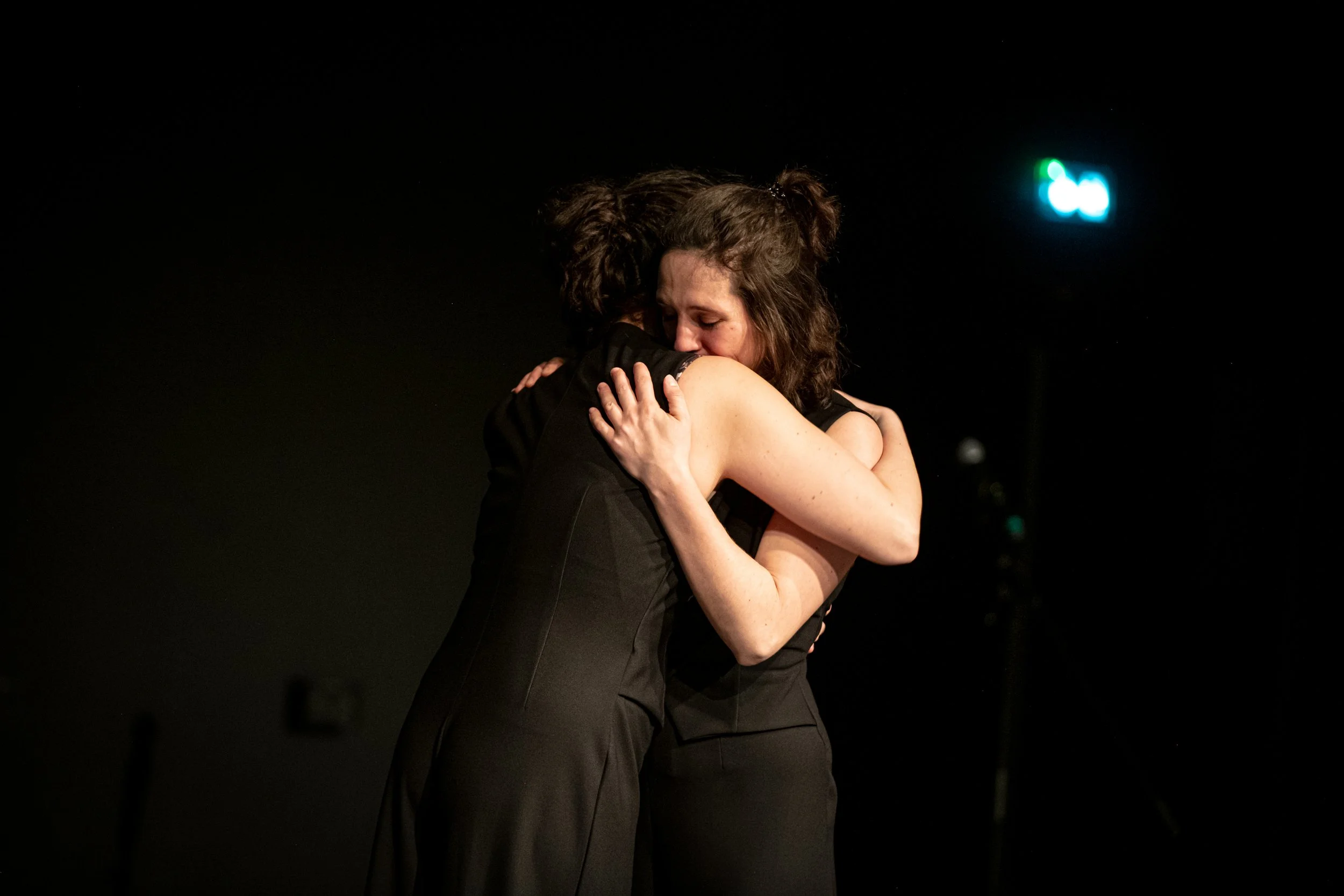 Deux femmes s'embrassent dans un endroit sombre.