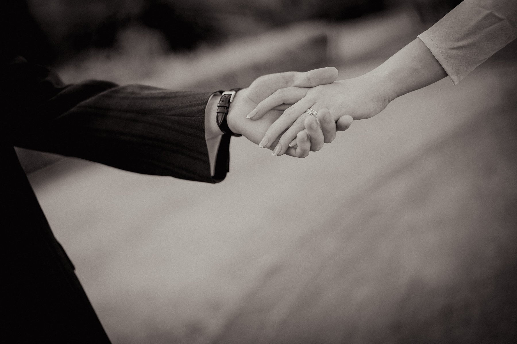 Close-up of a handshake between two people, one in a dark business suit and the other in a light-colored shirt, symbolizing agreement or partnership.