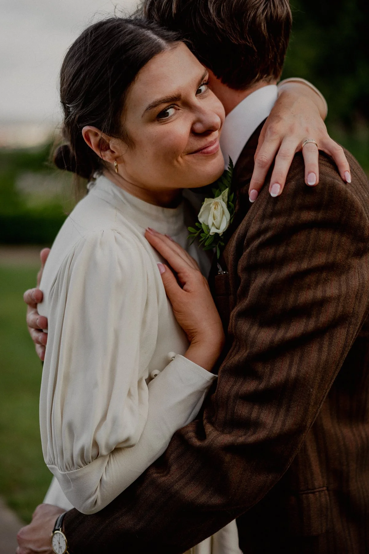 A woman smiling and hugging a man dressed in vintage clothing outdoors.