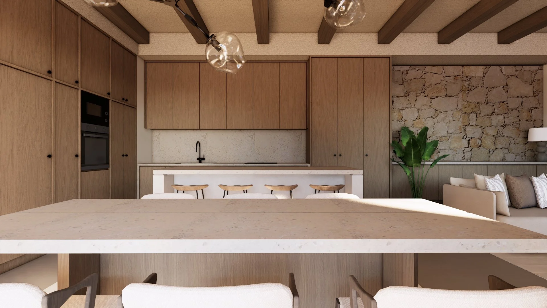 Interior view of a modern kitchen with wooden cabinets, a white countertop, a black faucet, and bar stools with natural wood seats. Part of a living area with a beige sofa, pillows, a lamp, and a large green plant. Exposed wooden beams on the ceiling and a stone accent wall.