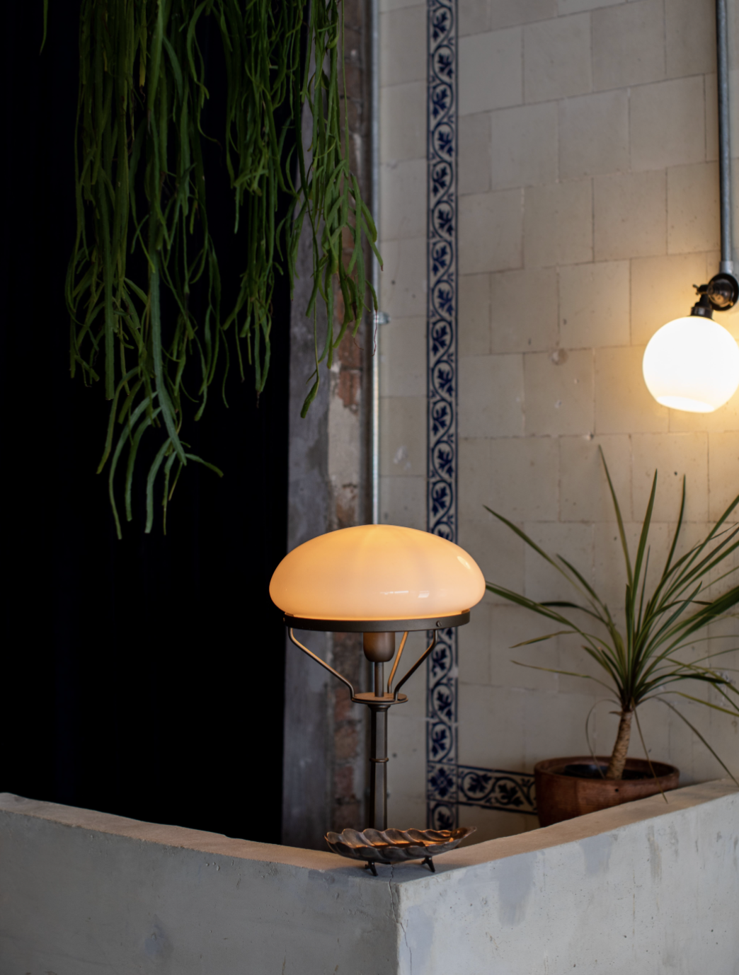 Interior with vintage tiles, antique lights, a striking front reception desk, plants and lush curtains.