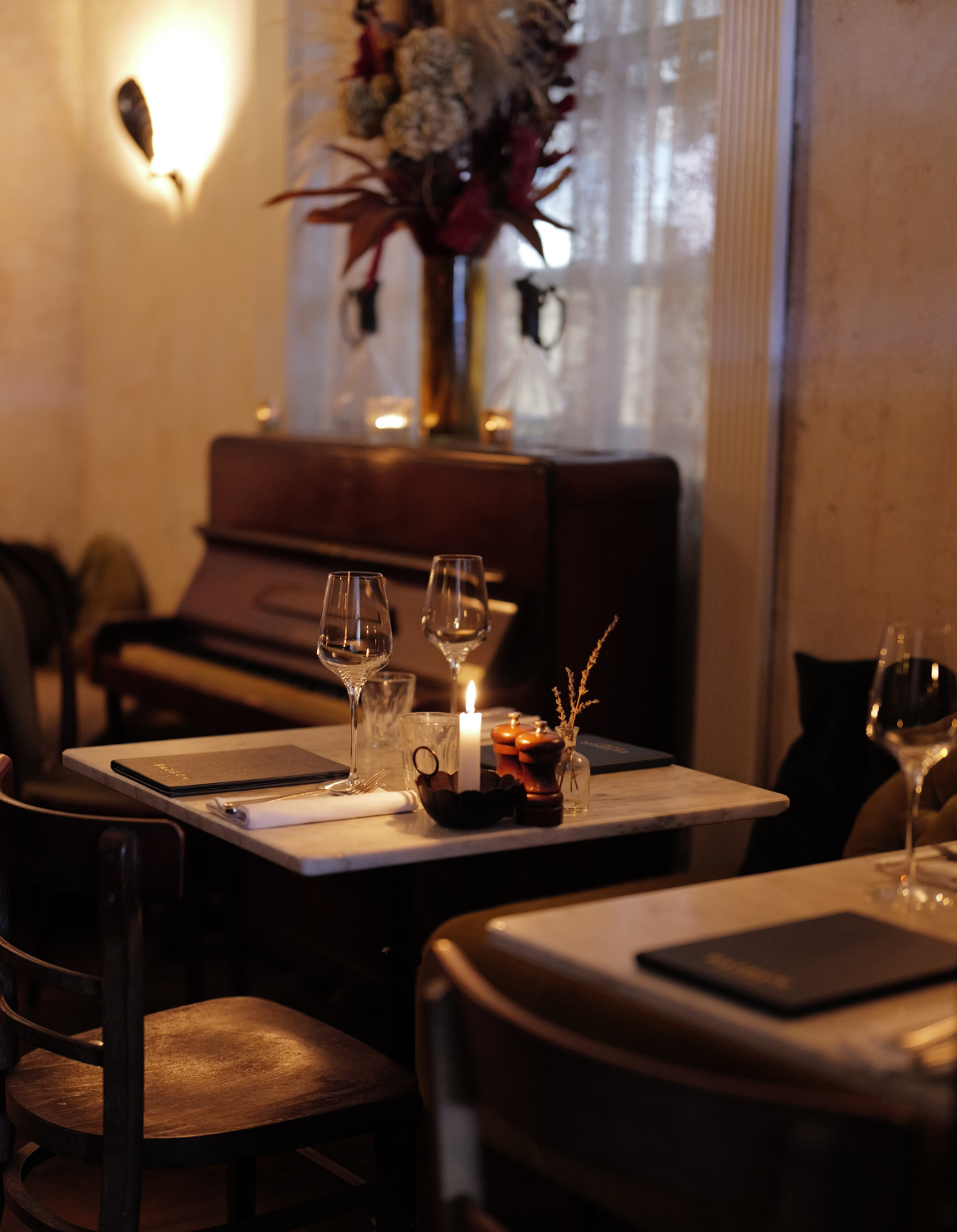 Marble tables set for dinner at a cosy spirit lounge at Patron restaurant, with warm ambient lighting, hand-pained ceiling, private bar and a vintage piano.
