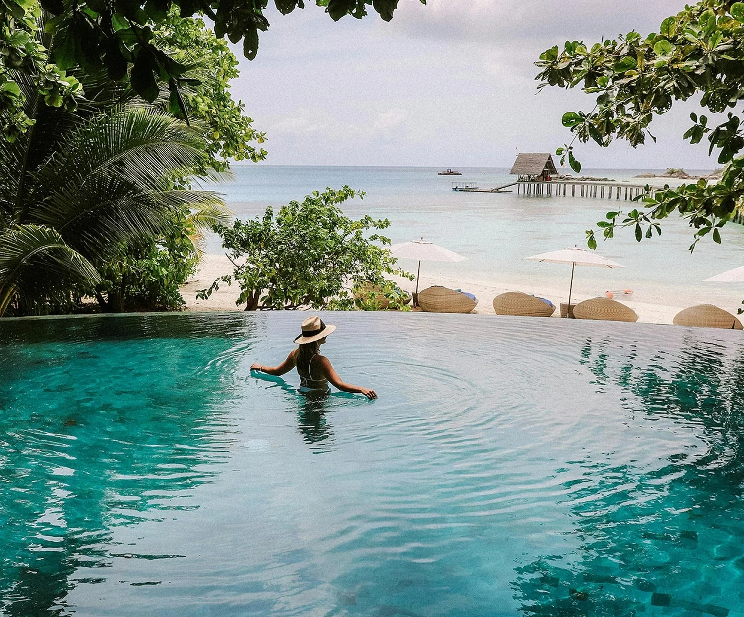 Signature stays. Remote island resort. Exclusive accommodation. Guest relaxing by a pool at a private island retreat.