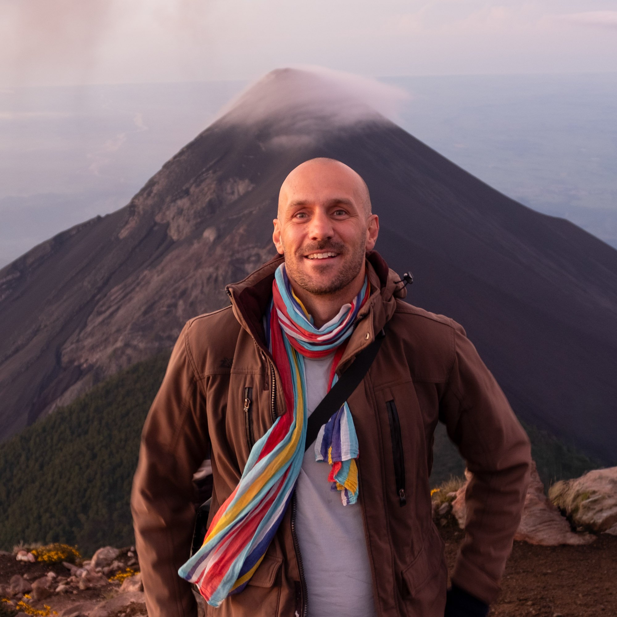 Graham French, founder of Origo, on Acatenango volcano, with erupting Fuego volcano behind. Guatemala