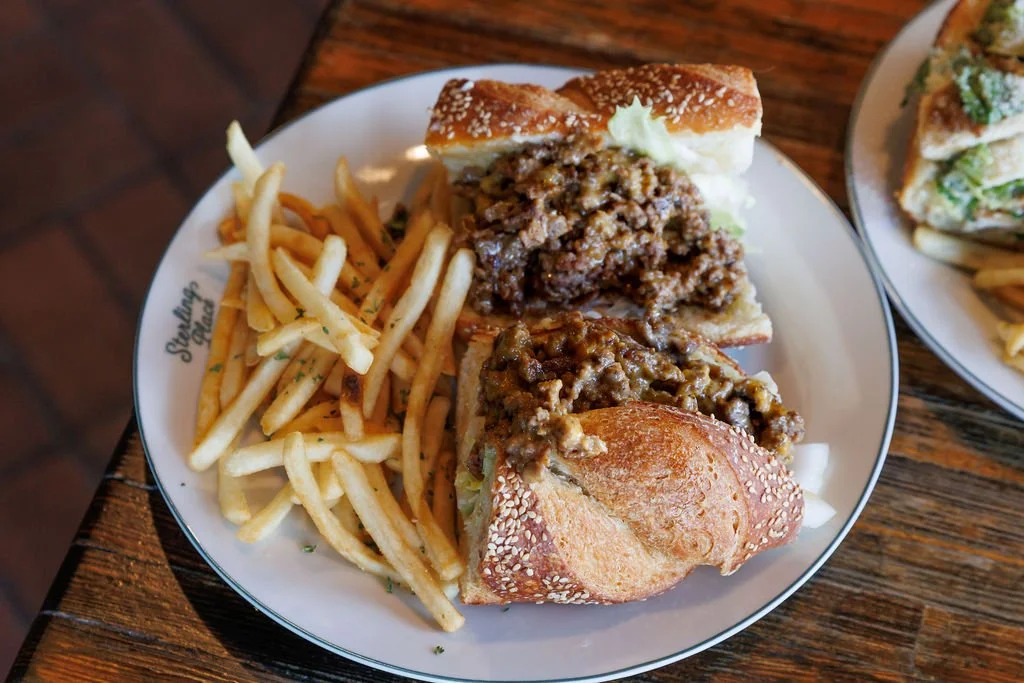 Cheeseburger sandwich with fries served on a white plate, with a side of shredded lettuce.