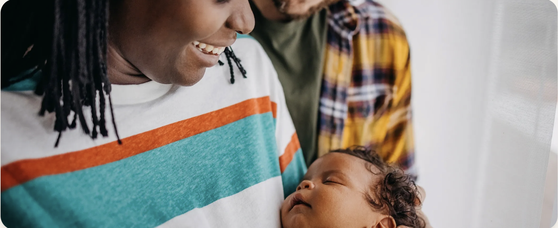A smiling person holding a sleeping baby.