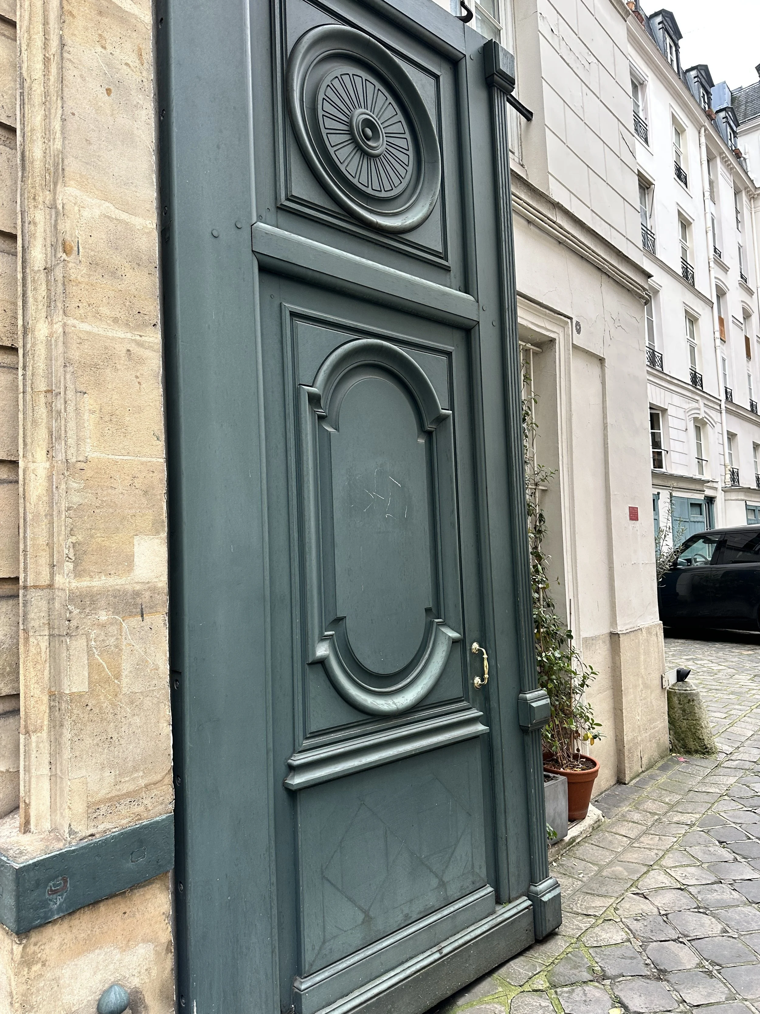 Tall historic green door with decorative molding set into a stone building facade.
