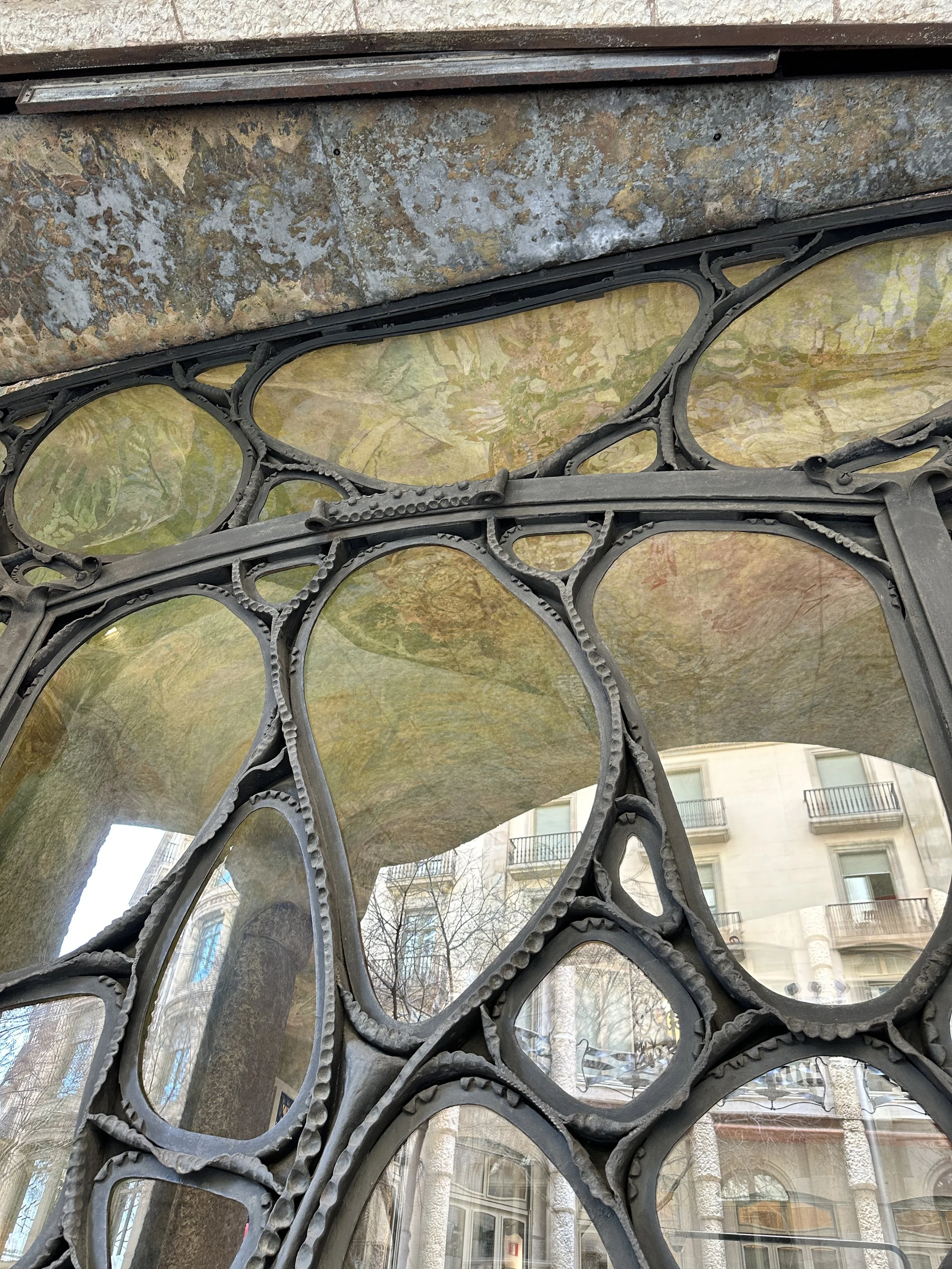 Close-up of decorative stained glass with organic black framing and softly colored glass panels.
