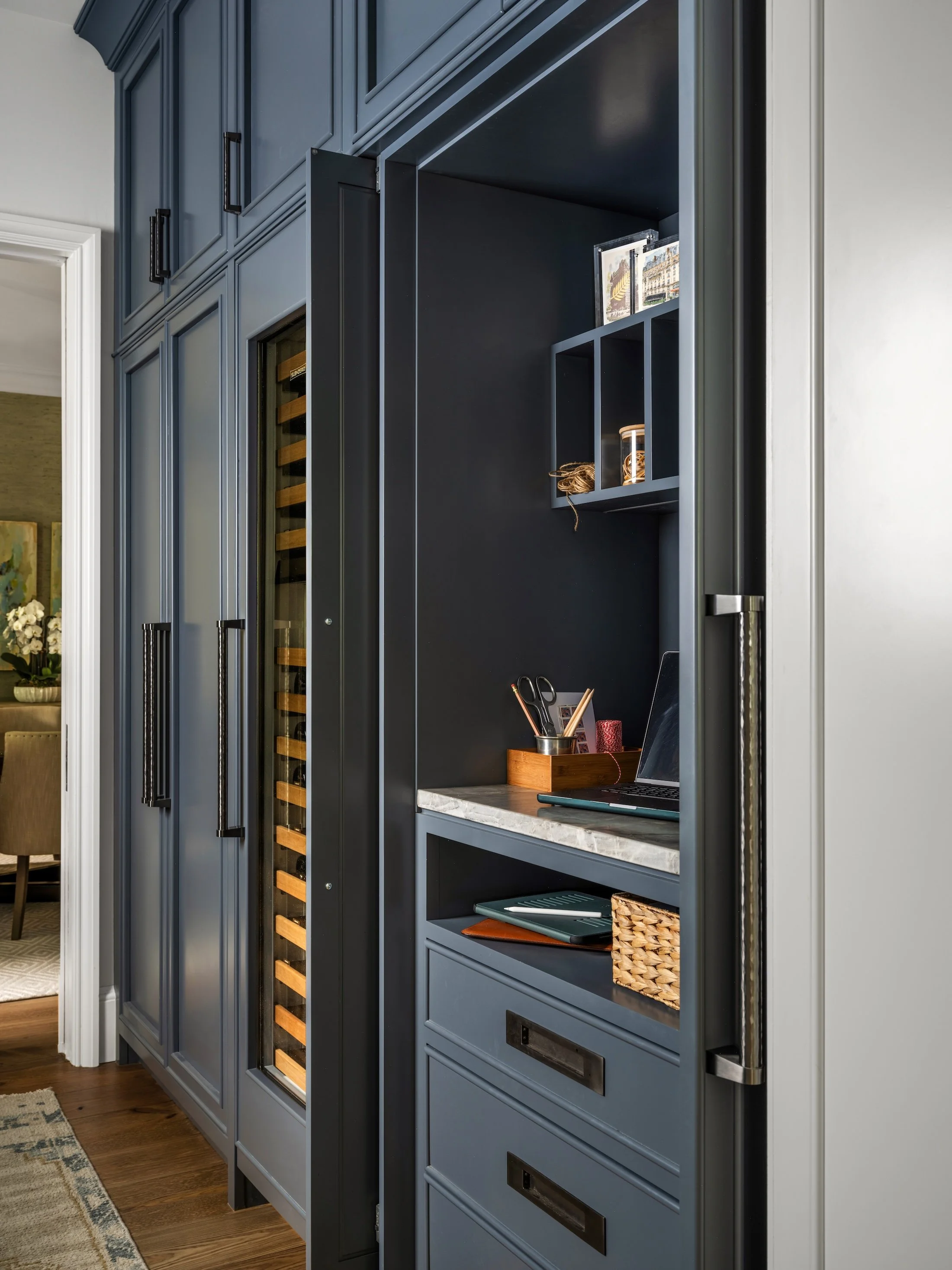 Tall navy built-in cabinetry with integrated wine storage, drawers, and open display shelving.