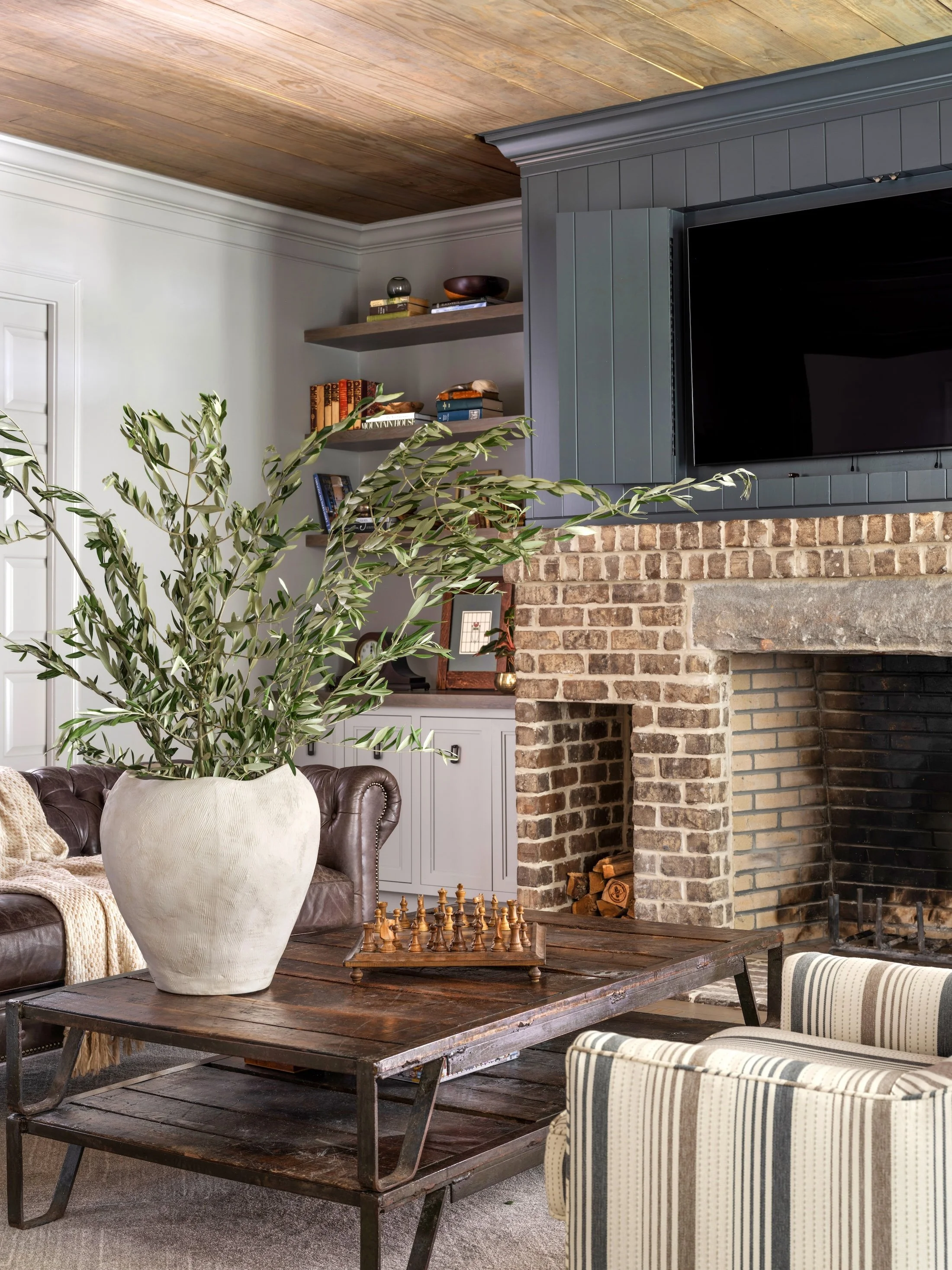 Collected family room with brick fireplace, dark built-ins, wood coffee table, and layered neutral furnishings.