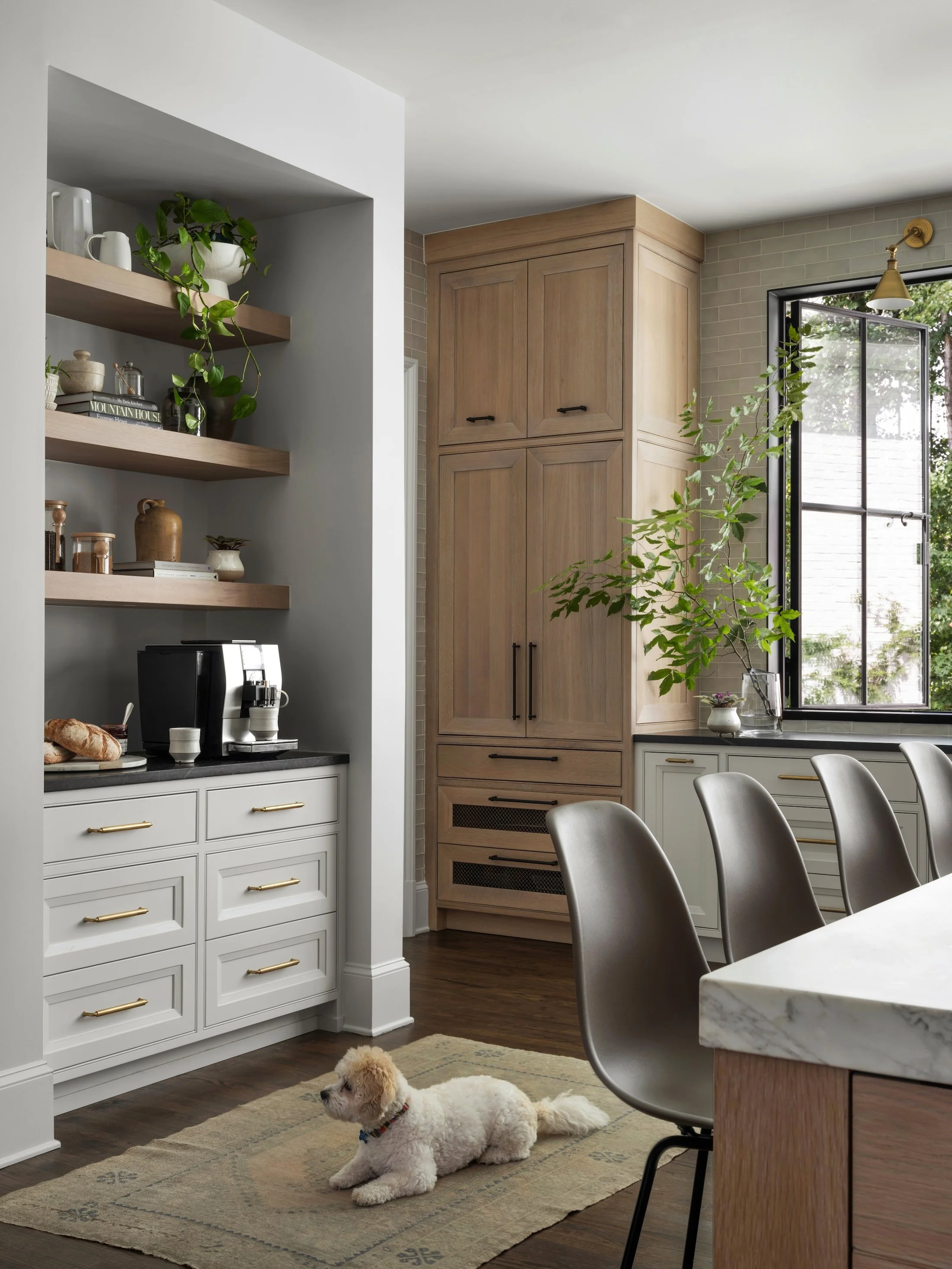 Custom kitchen storage with natural wood cabinetry, open shelving, black-framed windows, and counter seating.
