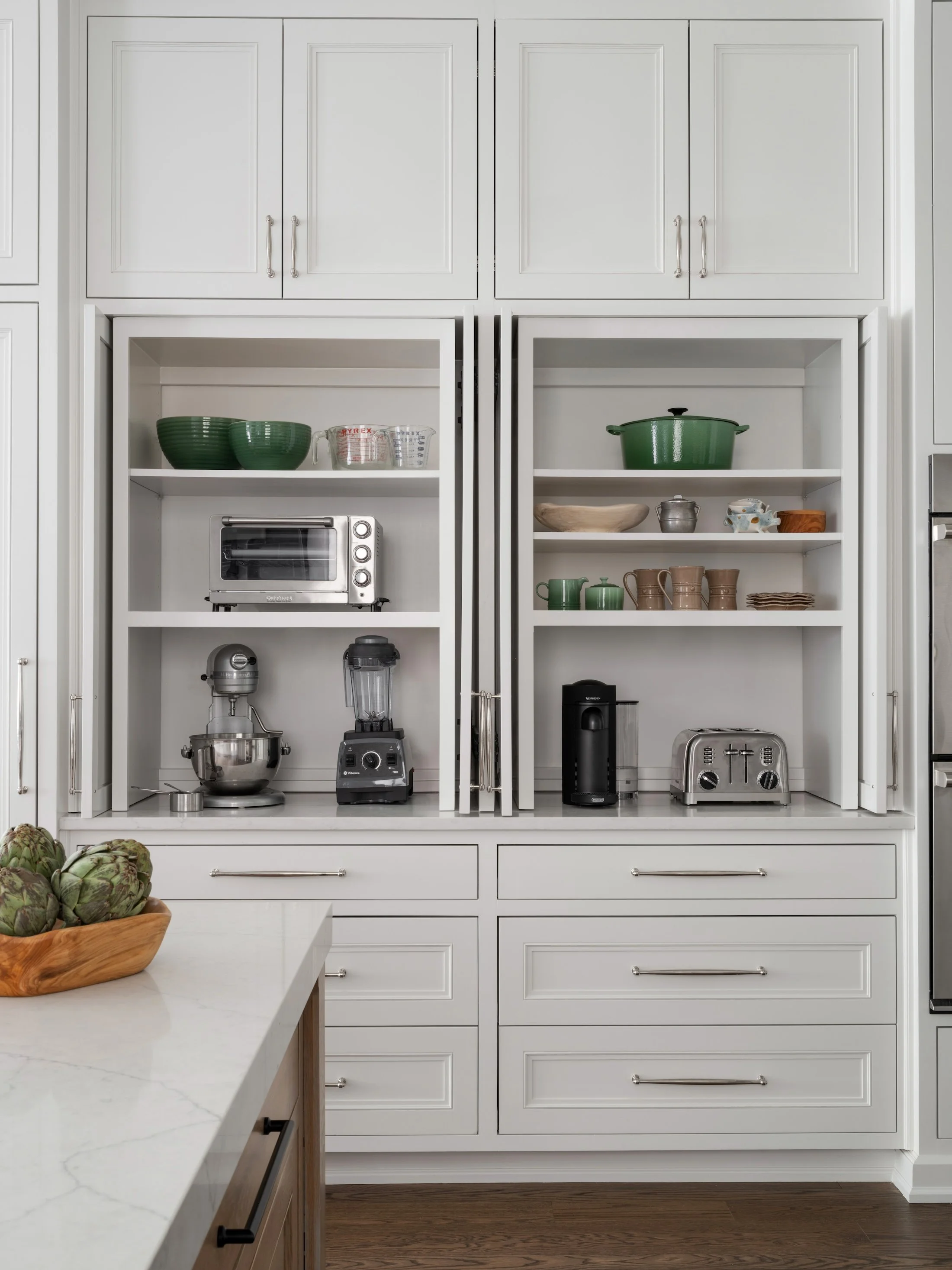 Built-in appliance pantry with white cabinetry, open shelves, countertop appliances, and organized kitchen storage.