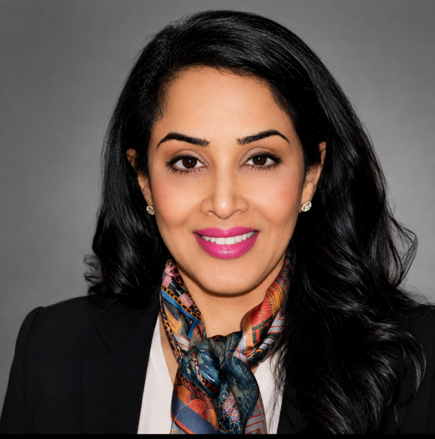 Professional woman with black hair, pink lipstick, wearing earrings, a patterned scarf, and a blazer, smiling against a gray background.