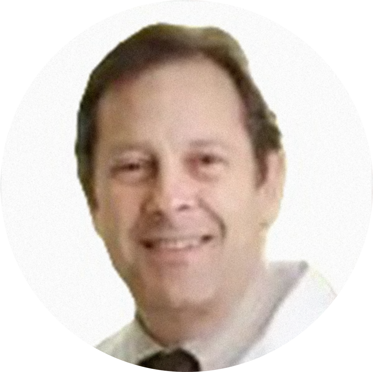 A smiling man with short dark hair, wearing a white shirt and a dark tie, against a white background.