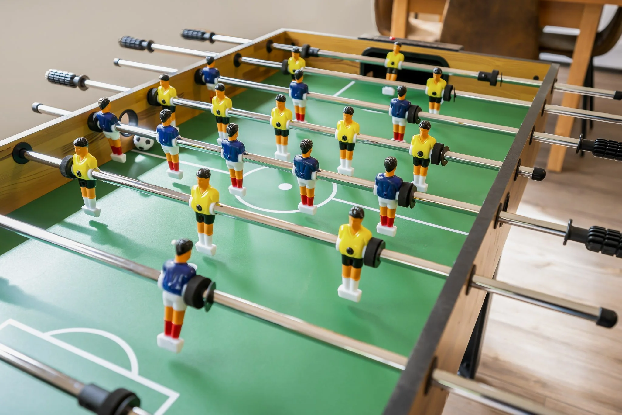 A foosball table with soccer player figures and miniature soccer balls on a green playing surface.