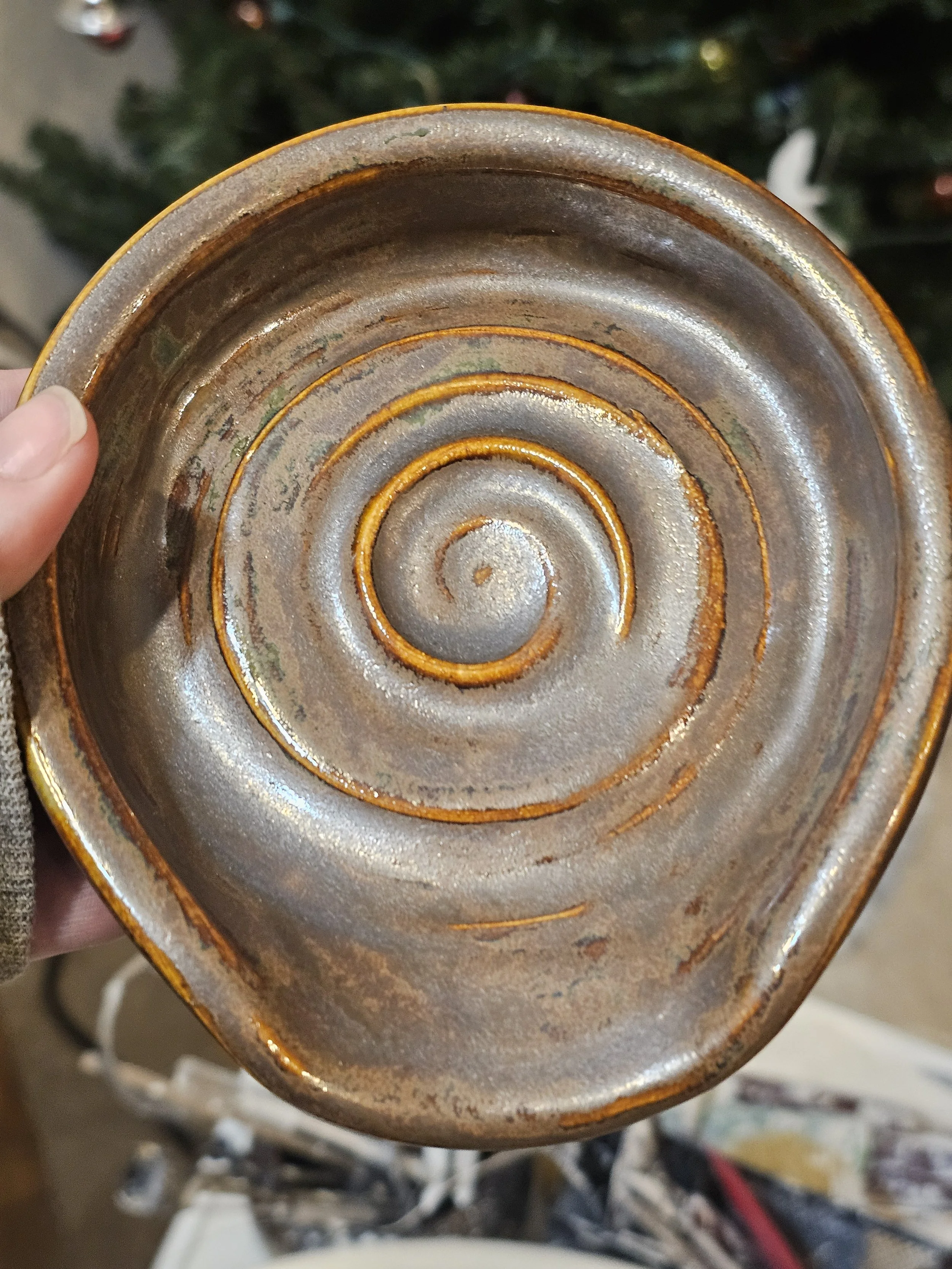 Close-up of the bottom of a pottery piece with concentric circles and a glossy, glazed interior surface, showing signs of age or wear.