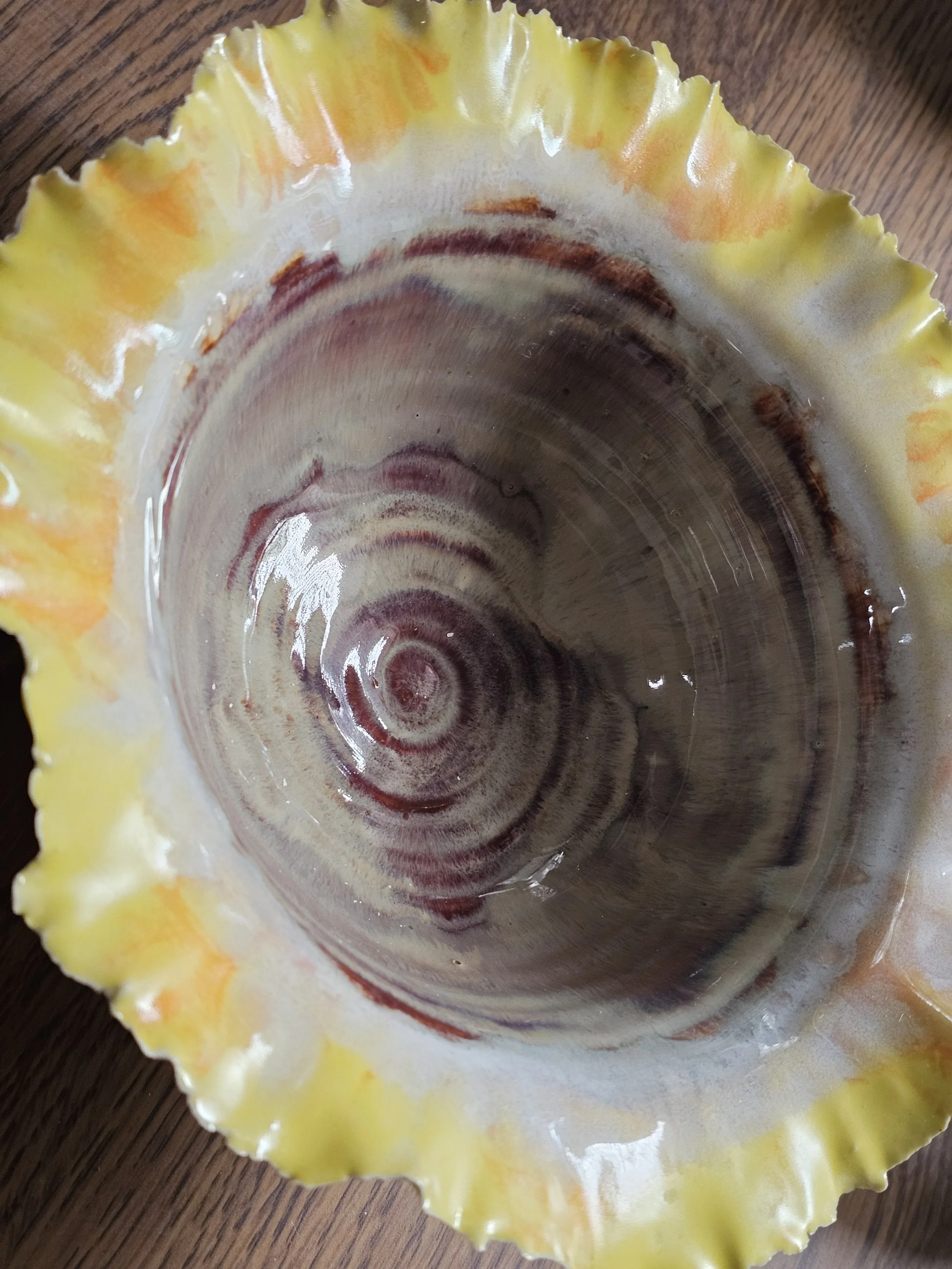 The inside view of a yellow ceramic bowl with a wooden surface underneath.