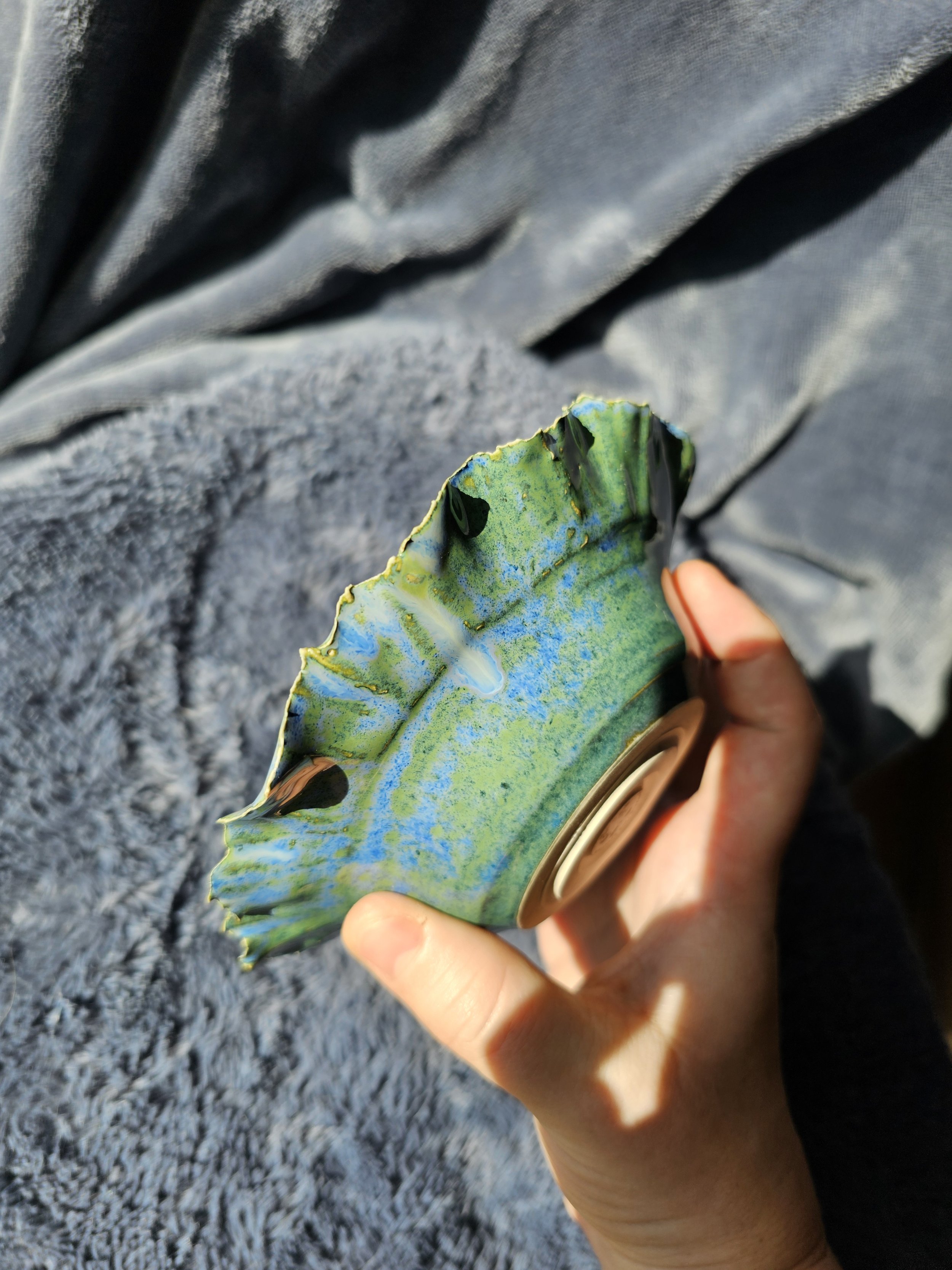 Person holding a multicolored, reflective ceramic bowl.