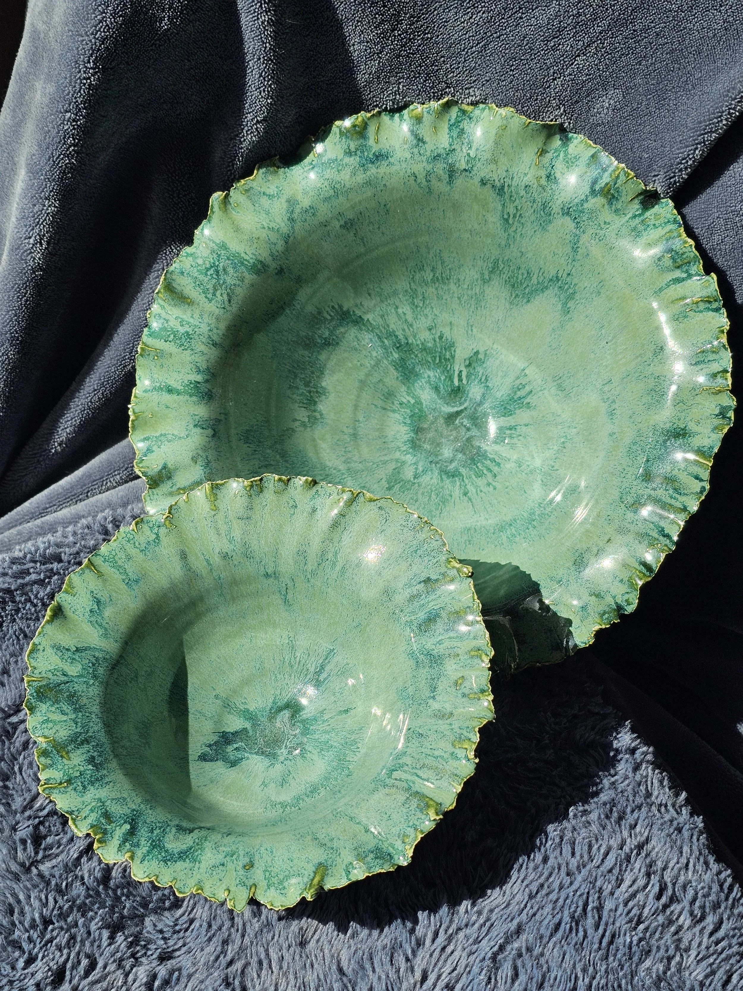 2 wheel-thrown ceramic bowls with a wavy edge and textured surface with green glaze.