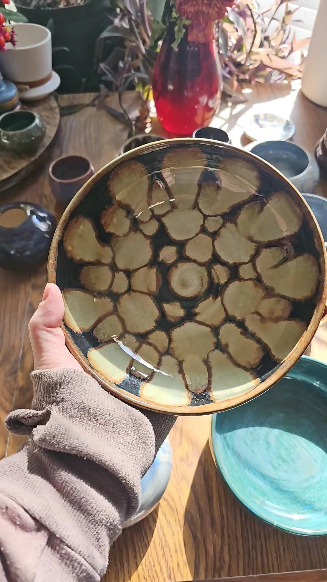 A person holding a ceramic bowl with a honeycomb pattern in a store filled with various ceramic pots and bowls.