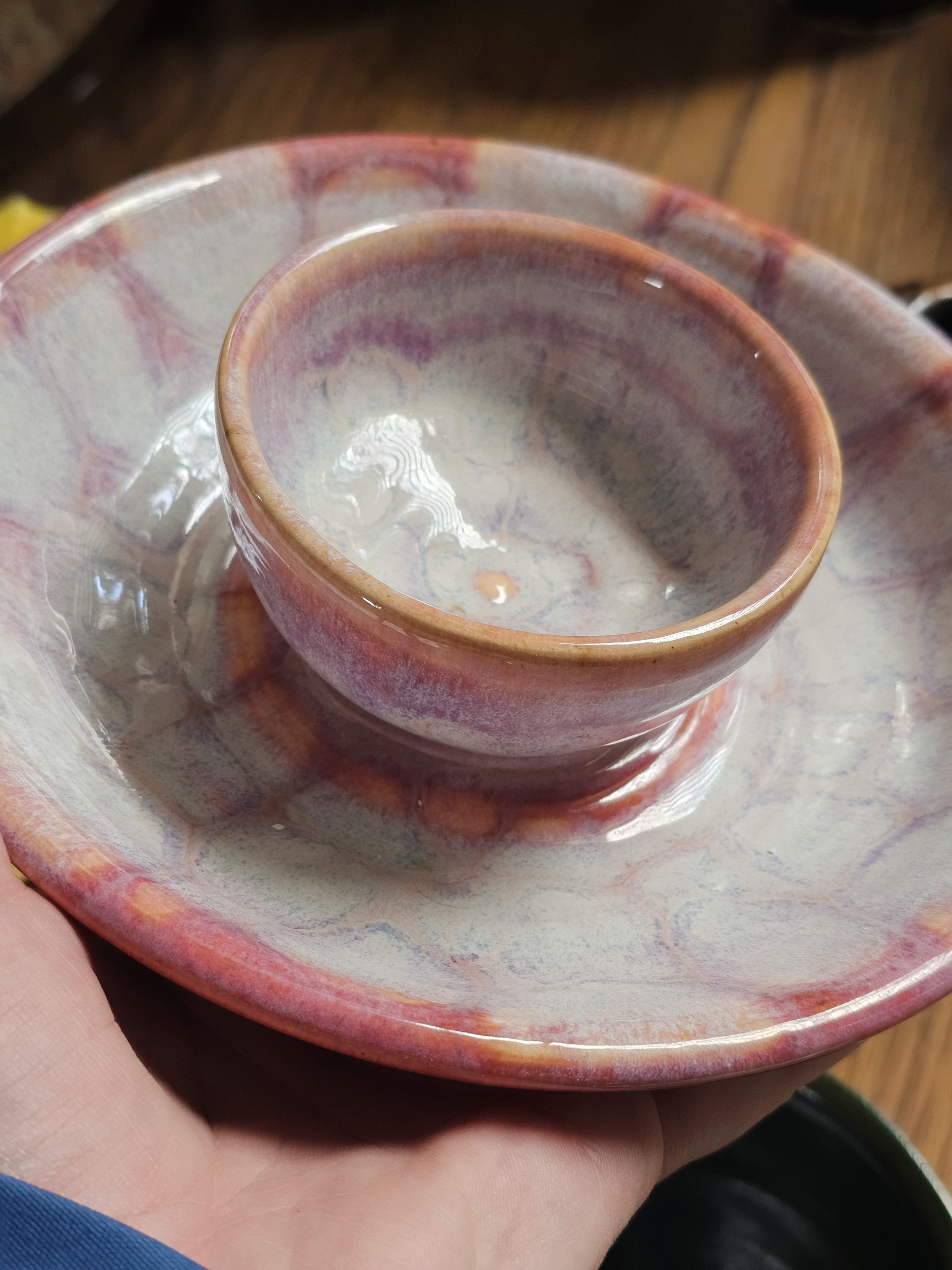 Close-up of a set of two maroon and cream-colored ceramic bowls, nested inside each other, on a silver tray.
