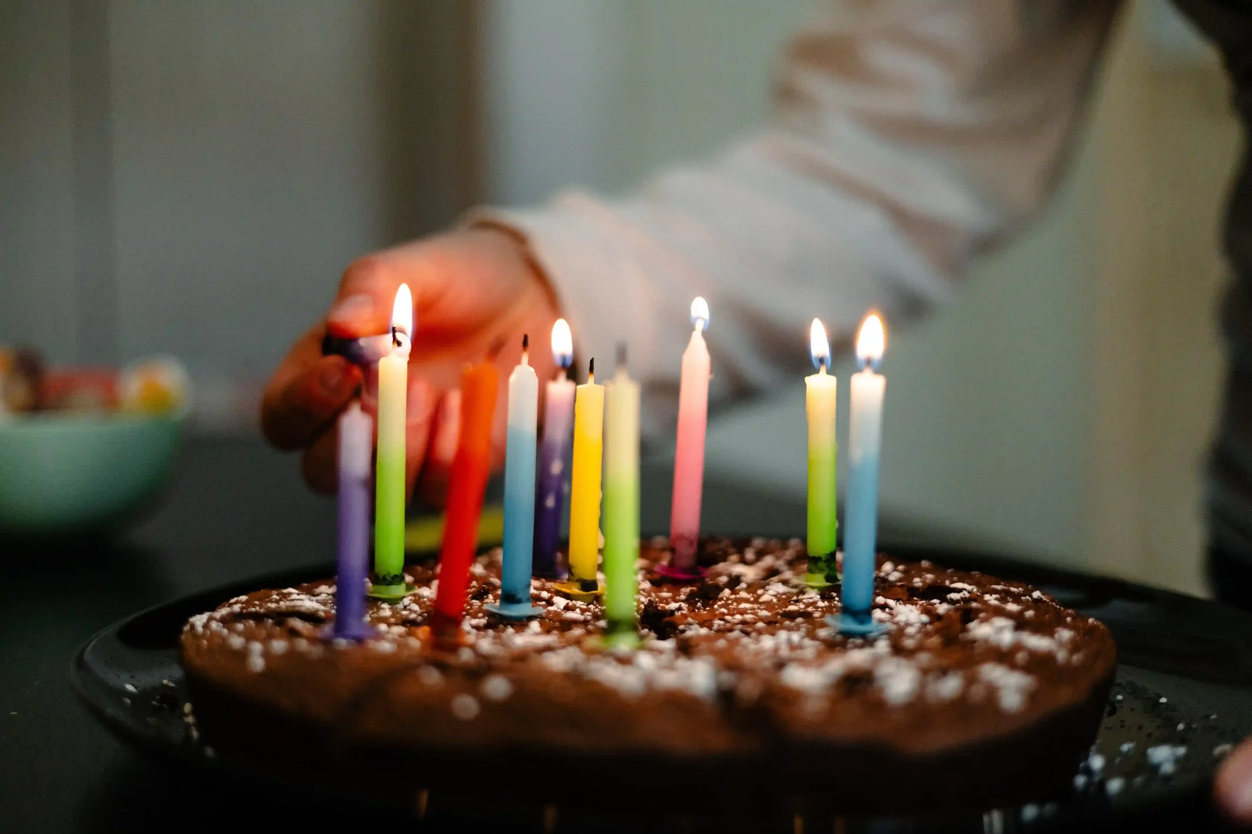 Gâteau d'anniversaire avec des bougies et une main qui les allument
