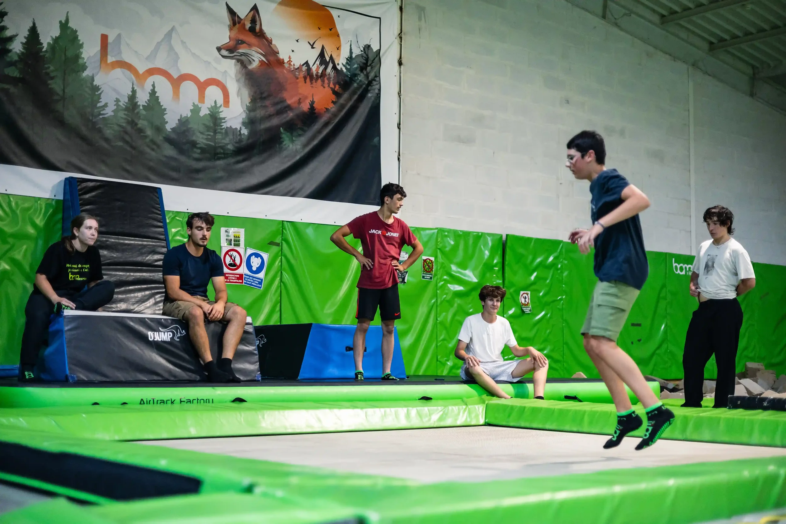 jeunes personnes autour d'un trampoline en train de regarder une autre personne en train de sauter sur un trampoline de BAM FREESPORTS