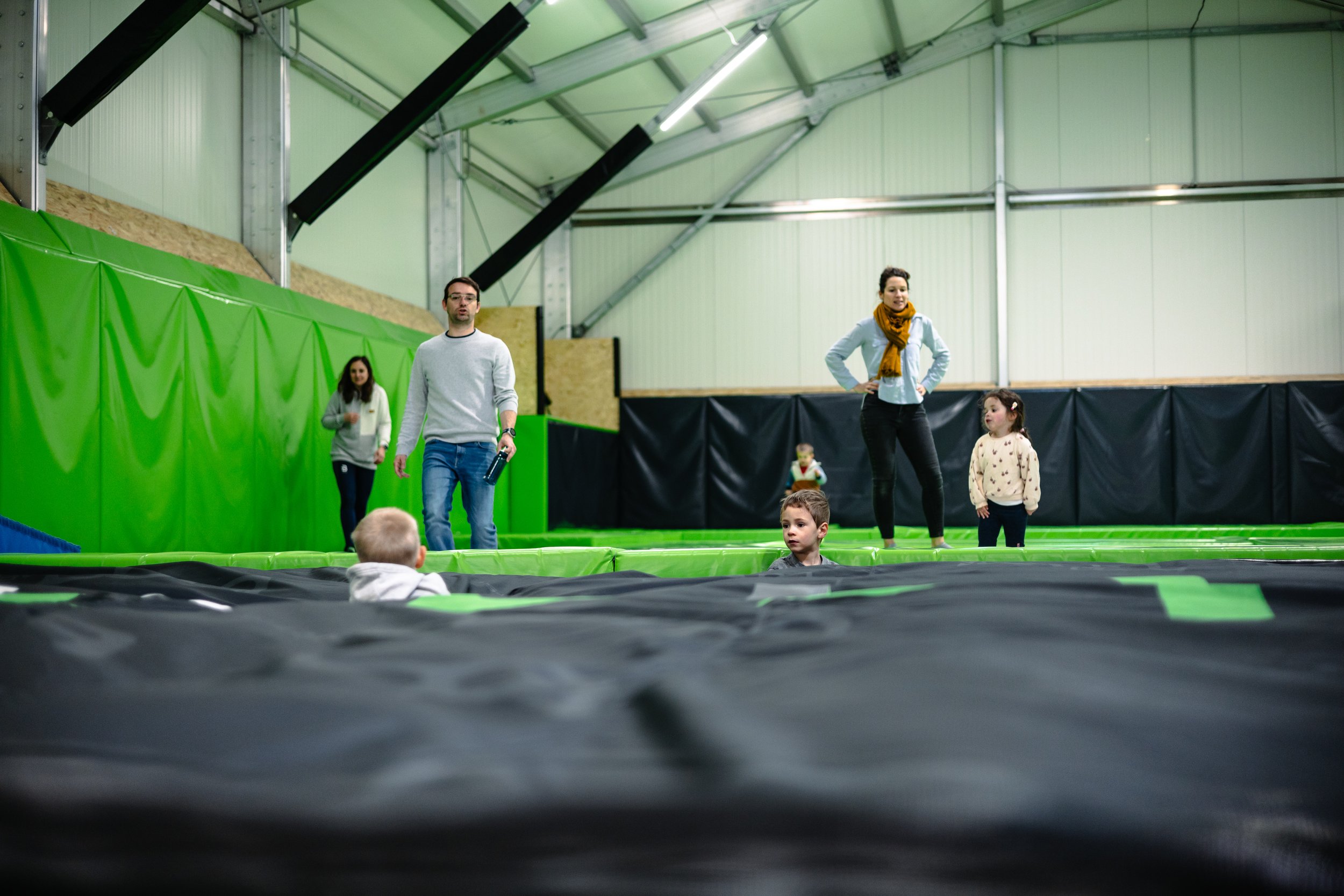 Petits enfants qui se cachent dans l'airbag accompagnés de leurs parents dans la salle de trampoline de BAM FREESPORTS