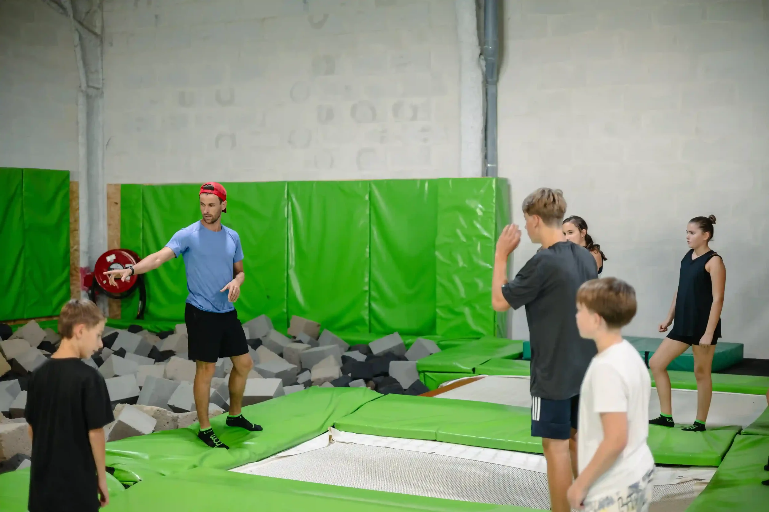 Jeunes pratiquants de trampoline freestyle qui s'entrainent dans la salle de BAM FREESPORTS Chambéry accompagnés d'un coach.