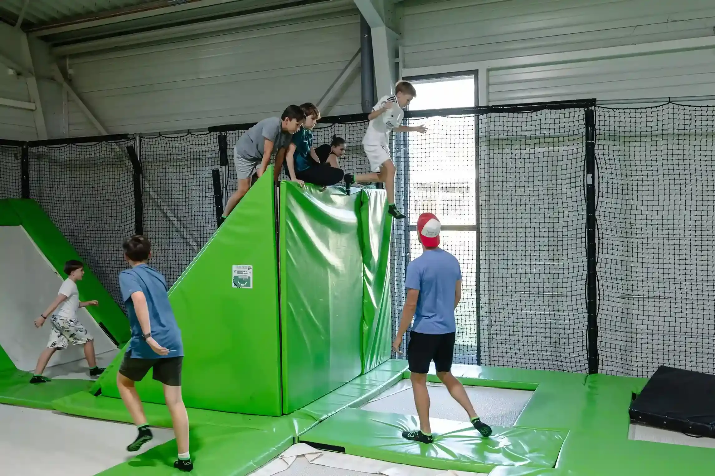 Coach des cours qui demande à ses élèves de sauter d'un mur pour atterrir sur un trampoline.