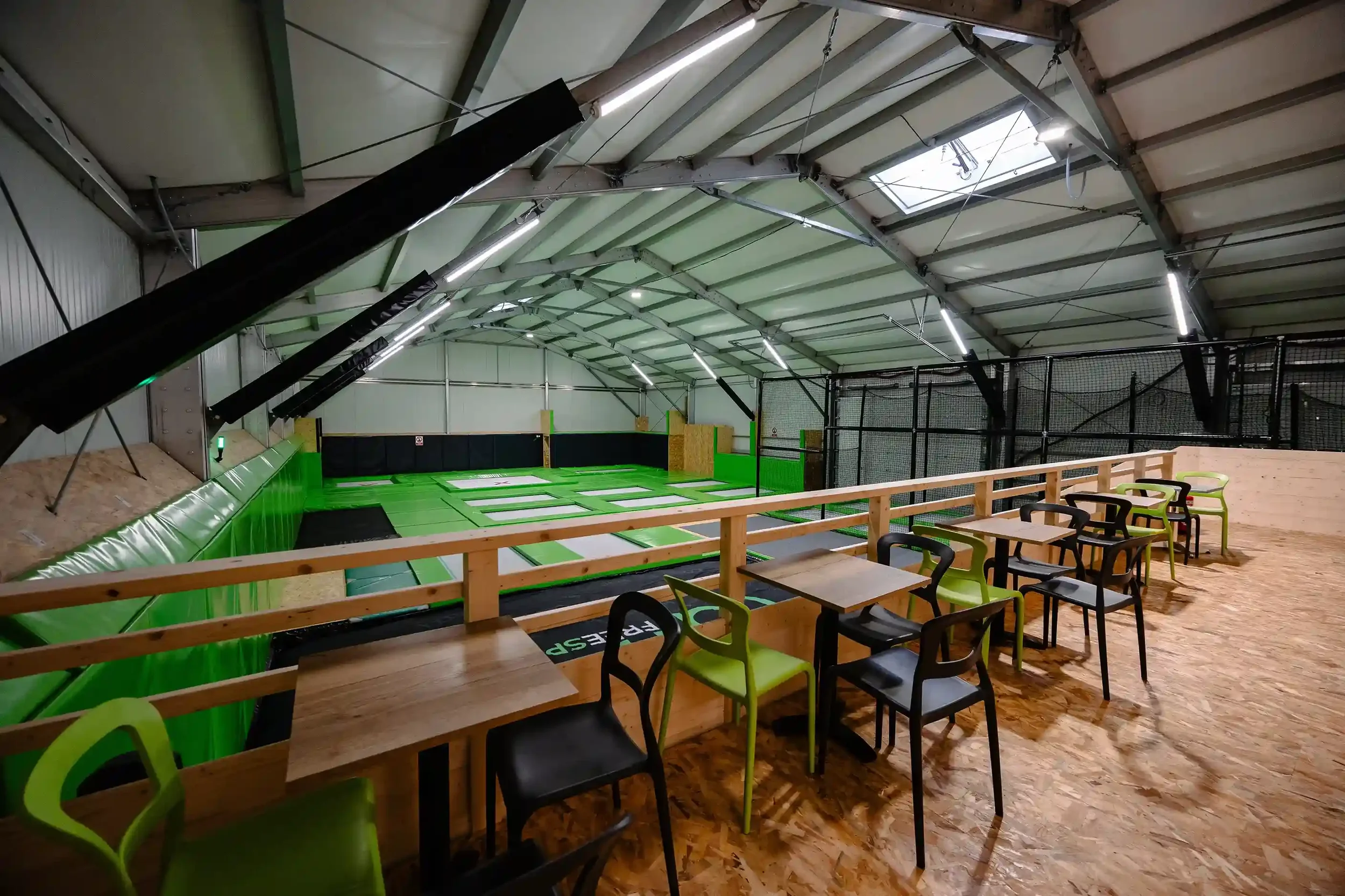 Salle de BAM FREESPORTS ANNECY, avec des tables et des chaises devant le trampoline