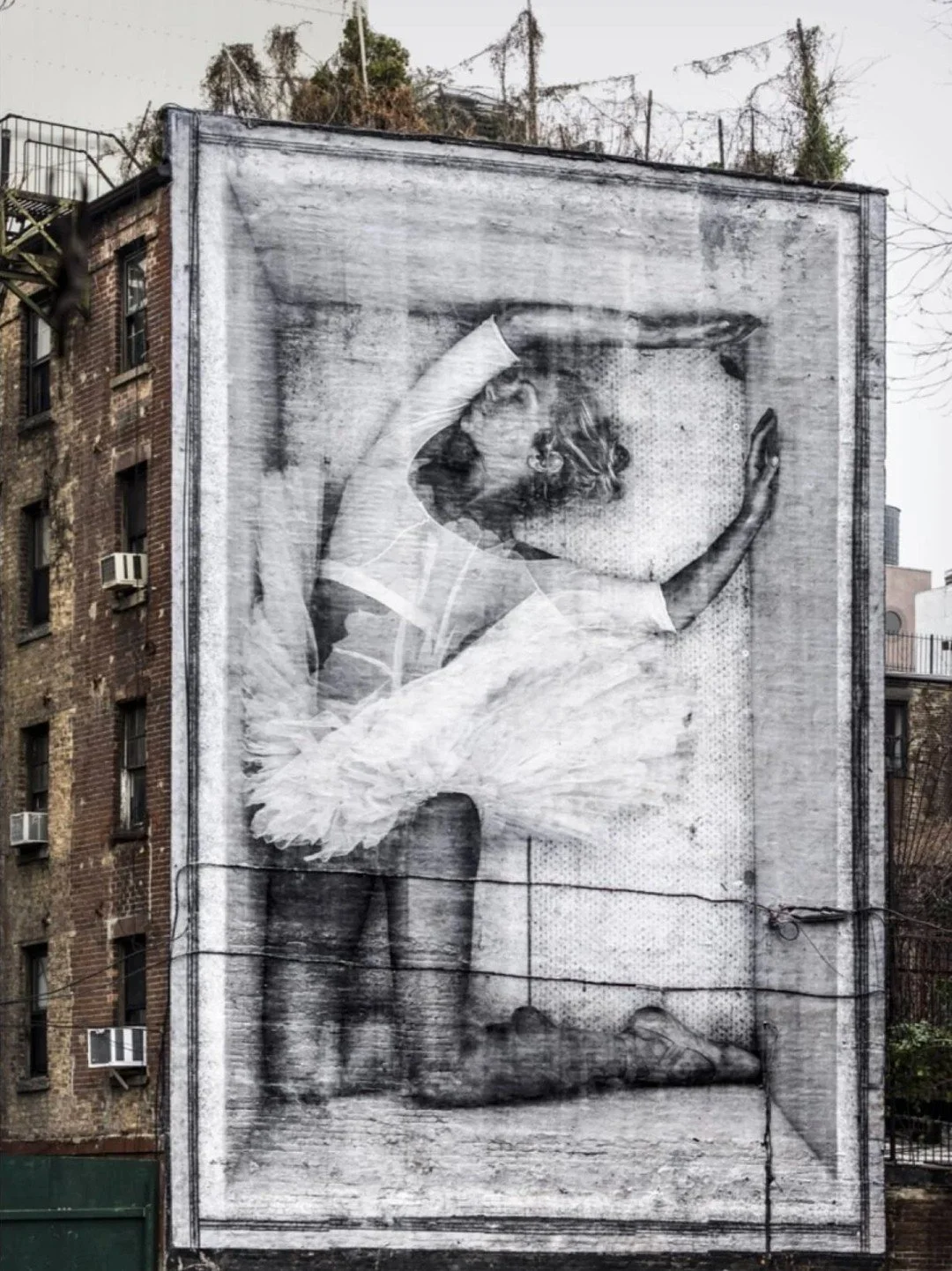 "Ballerina in a Crate" &mdash; JR, 2015

In December 2015, French street artist JR pasted a massive photograph onto a building in Manhattan's Lower East Side: Charlotte Ranson, a dancer with the Paris Opera Ballet, curled up asleep inside a