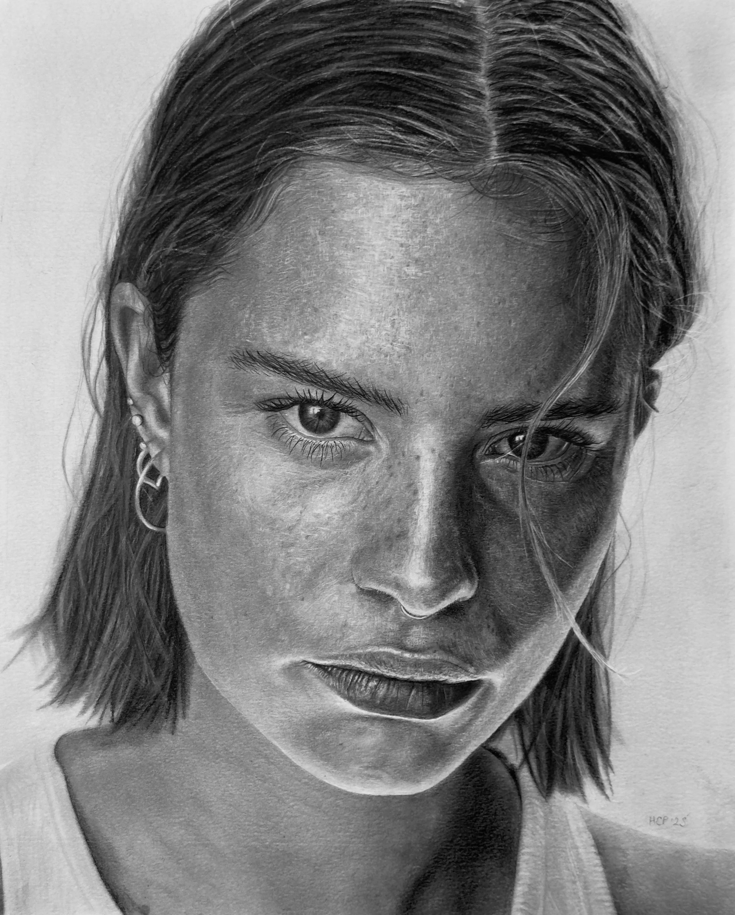 A black-and-white portrait of a young woman with straight hair, one eye visible, wearing earrings, with part of her face and neck shown.