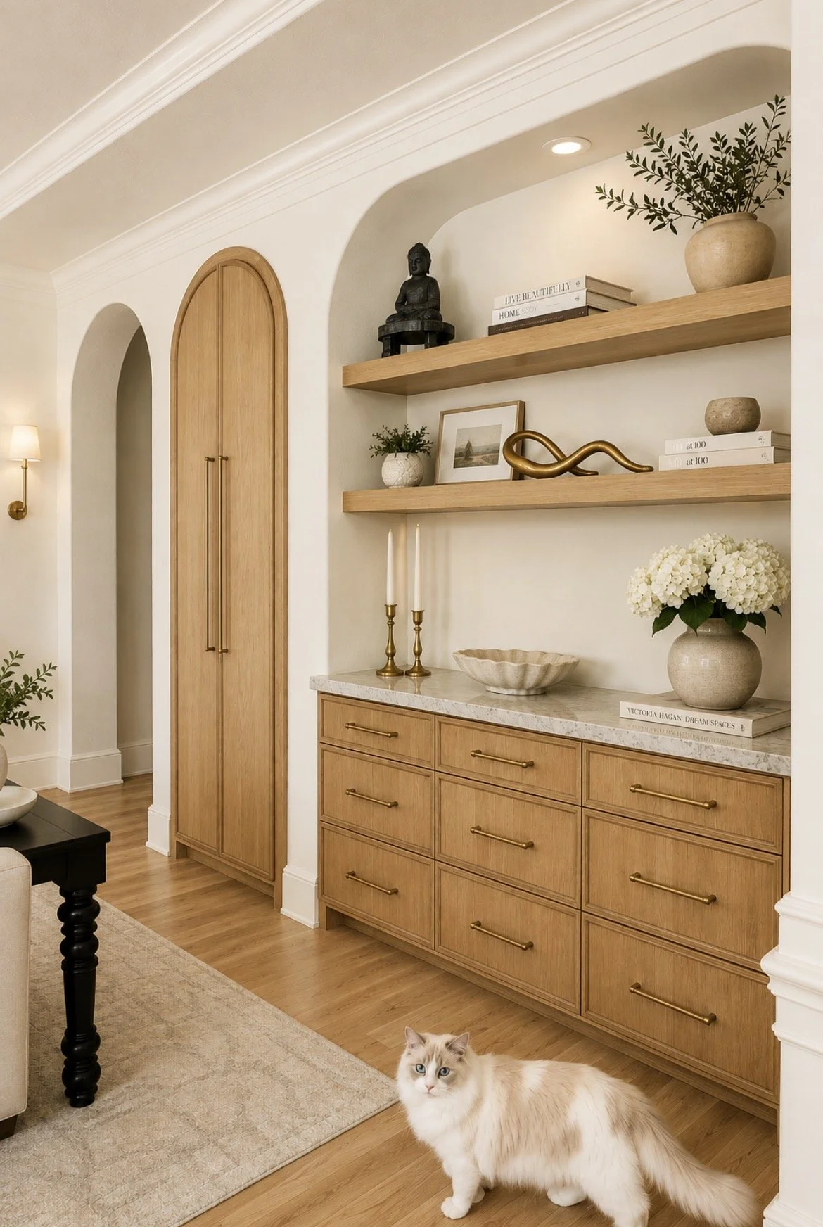 Custom white oak cabinetry with marble countertop, floating shelves, brass hardware and arched doorway