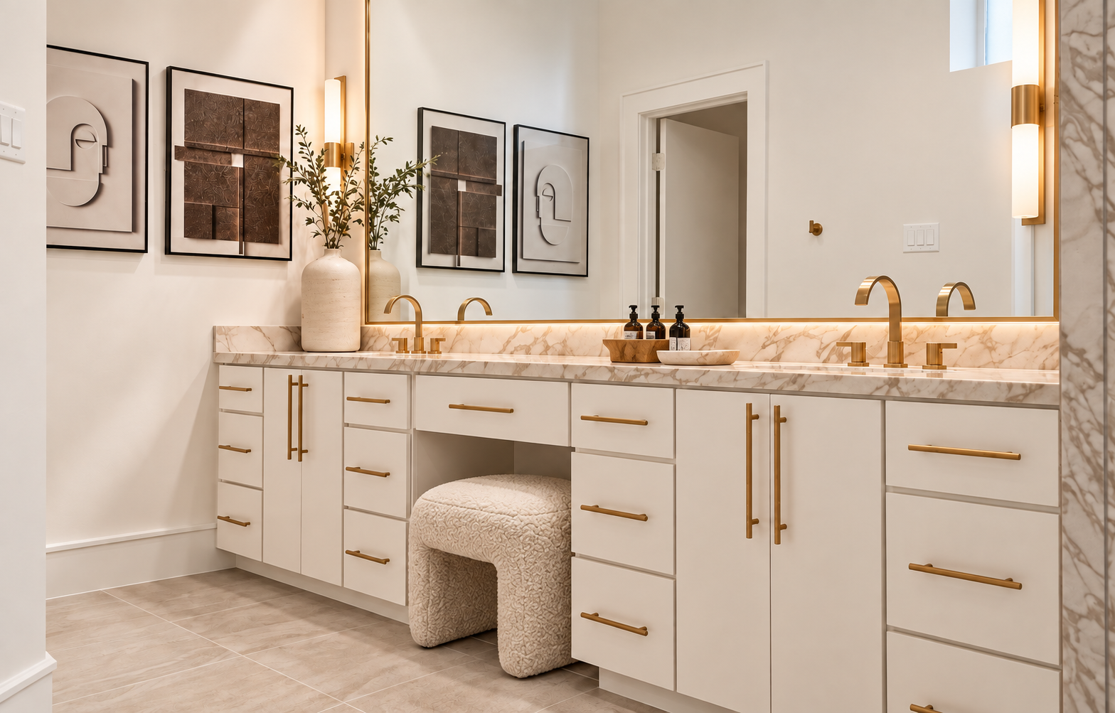 Double bathroom vanity with white cabinetry, stone countertop, brass fixtures and upholstered vanity stool.