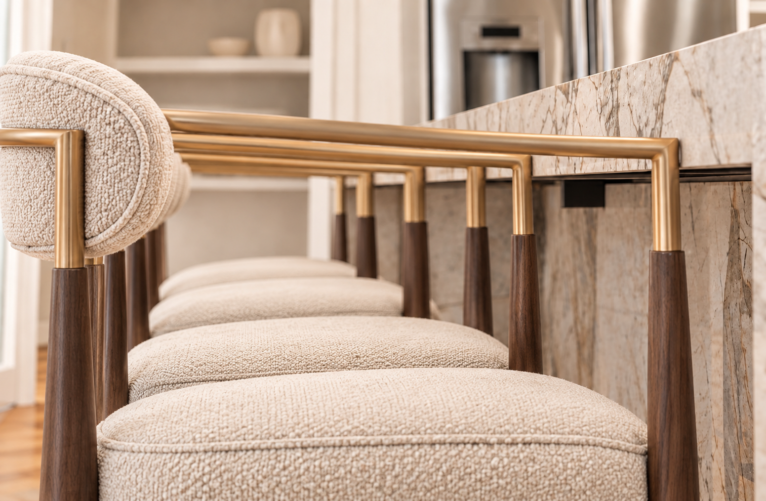 Close view of upholstered counter stools with curved wood frames beside brass-accented cabinetry.
