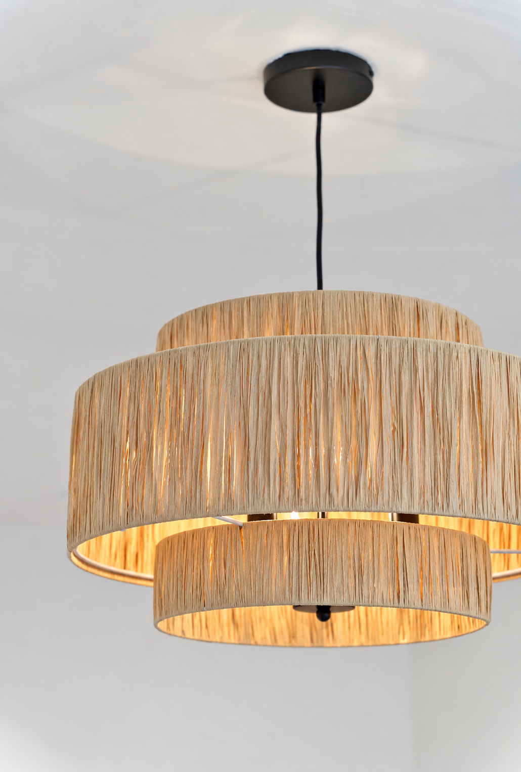 Sculptural tiered woven pendant light with warm natural fibers and softly diffused illumination.