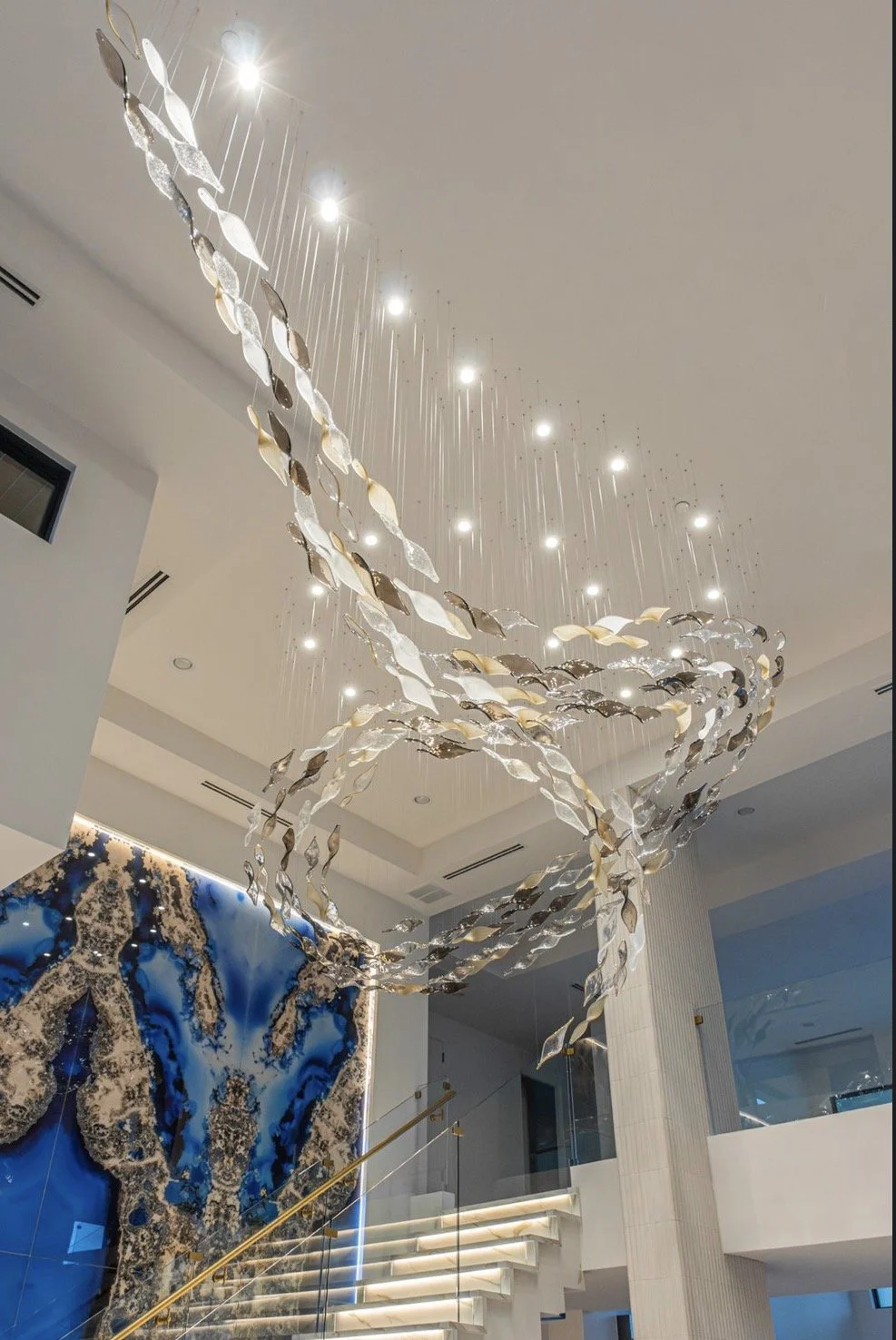 Detailed view of flowing metallic light forms suspended from the ceiling beside a dramatic stone installation.